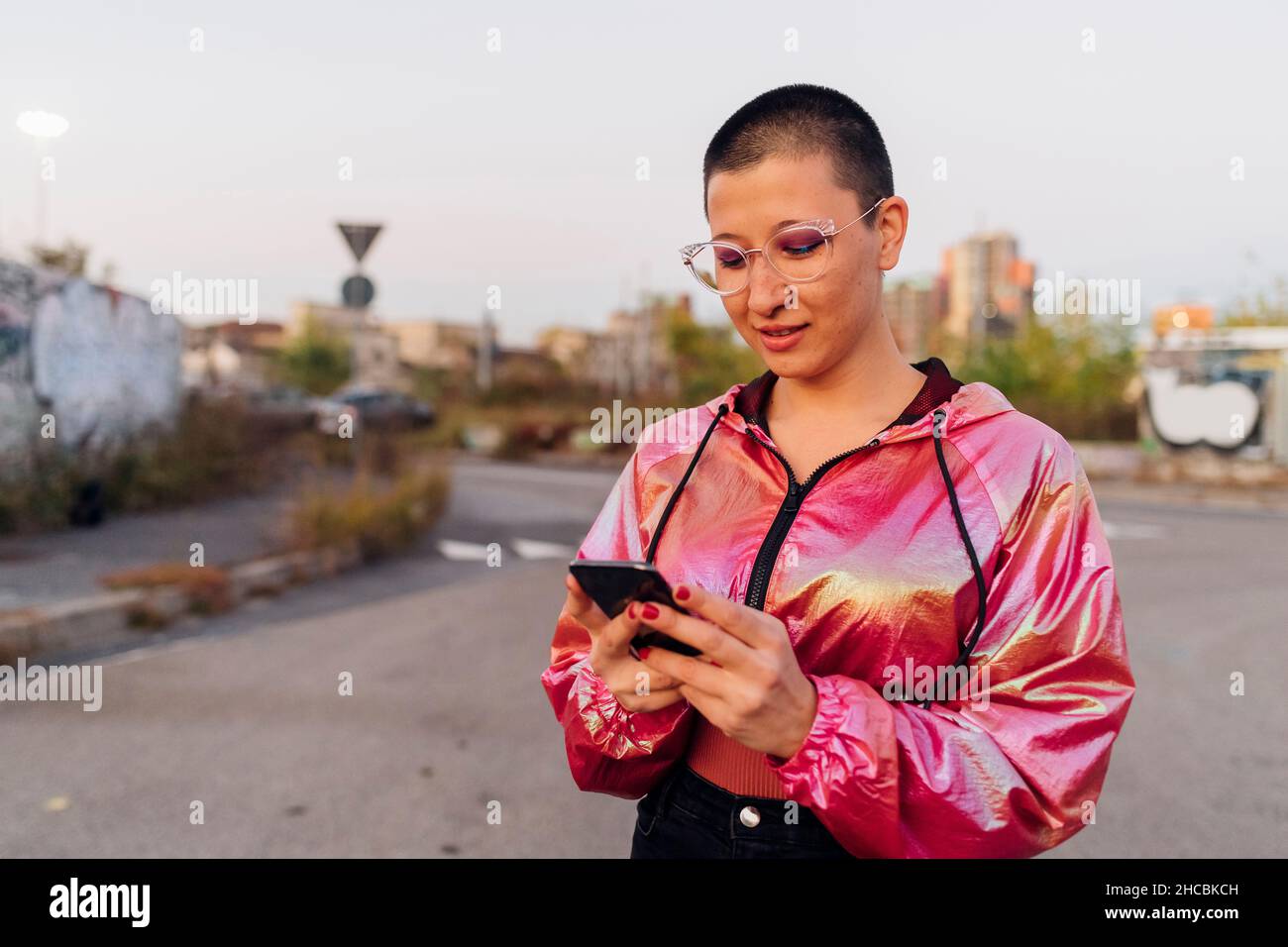 Frau mit rosa Jacke mit Handy auf der Straße Stockfoto