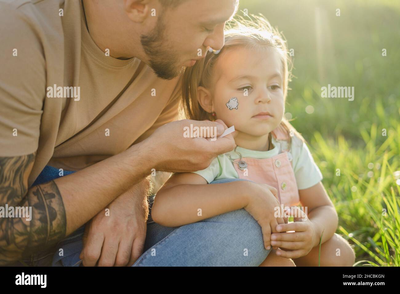 Mädchen mit Tätowierung im Gesicht sitzend mit Vater von Pflanzen Stockfoto
