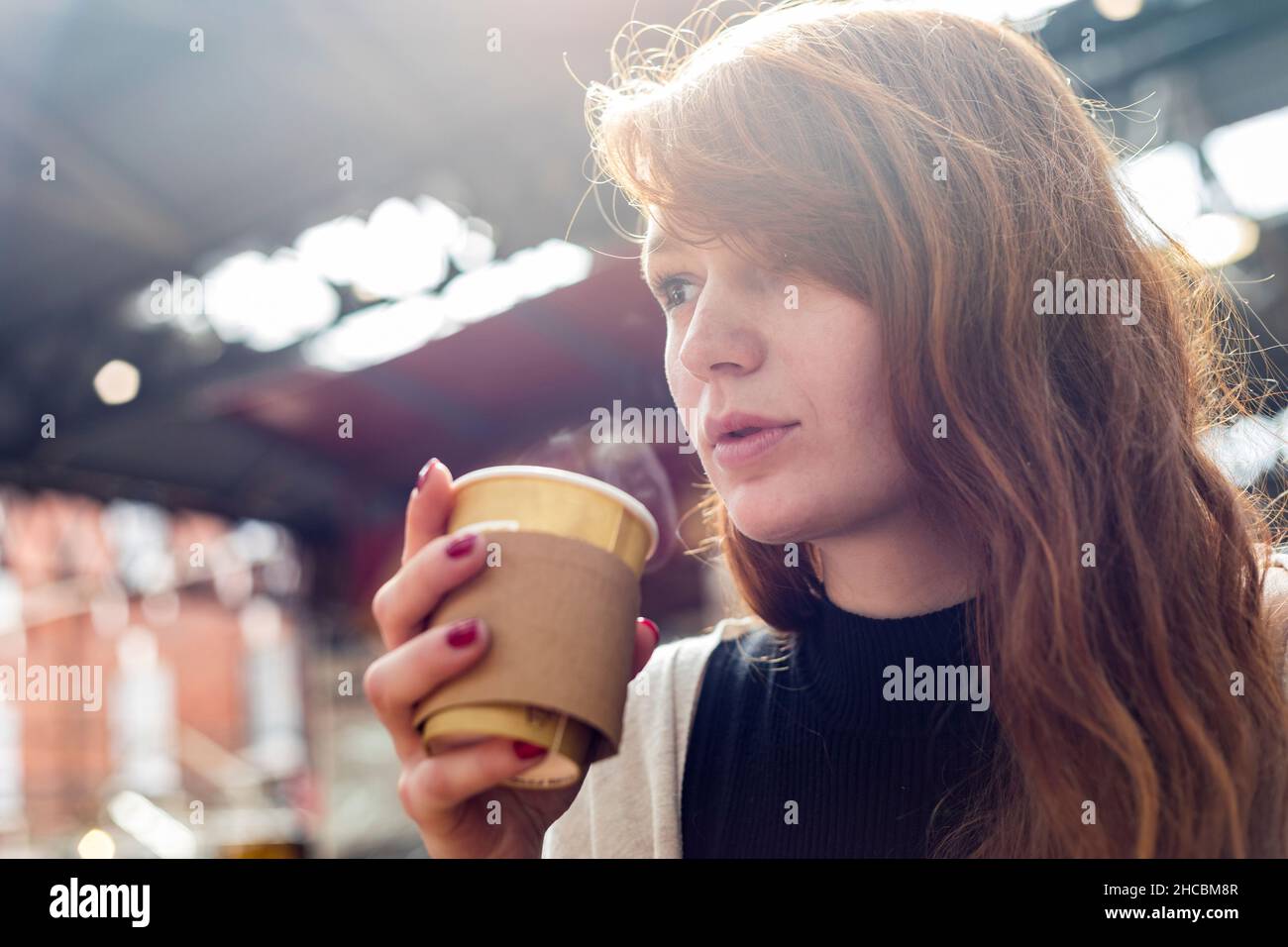 Junge Frau mit Kaffee in Einweg-Tasse im Café Stockfoto