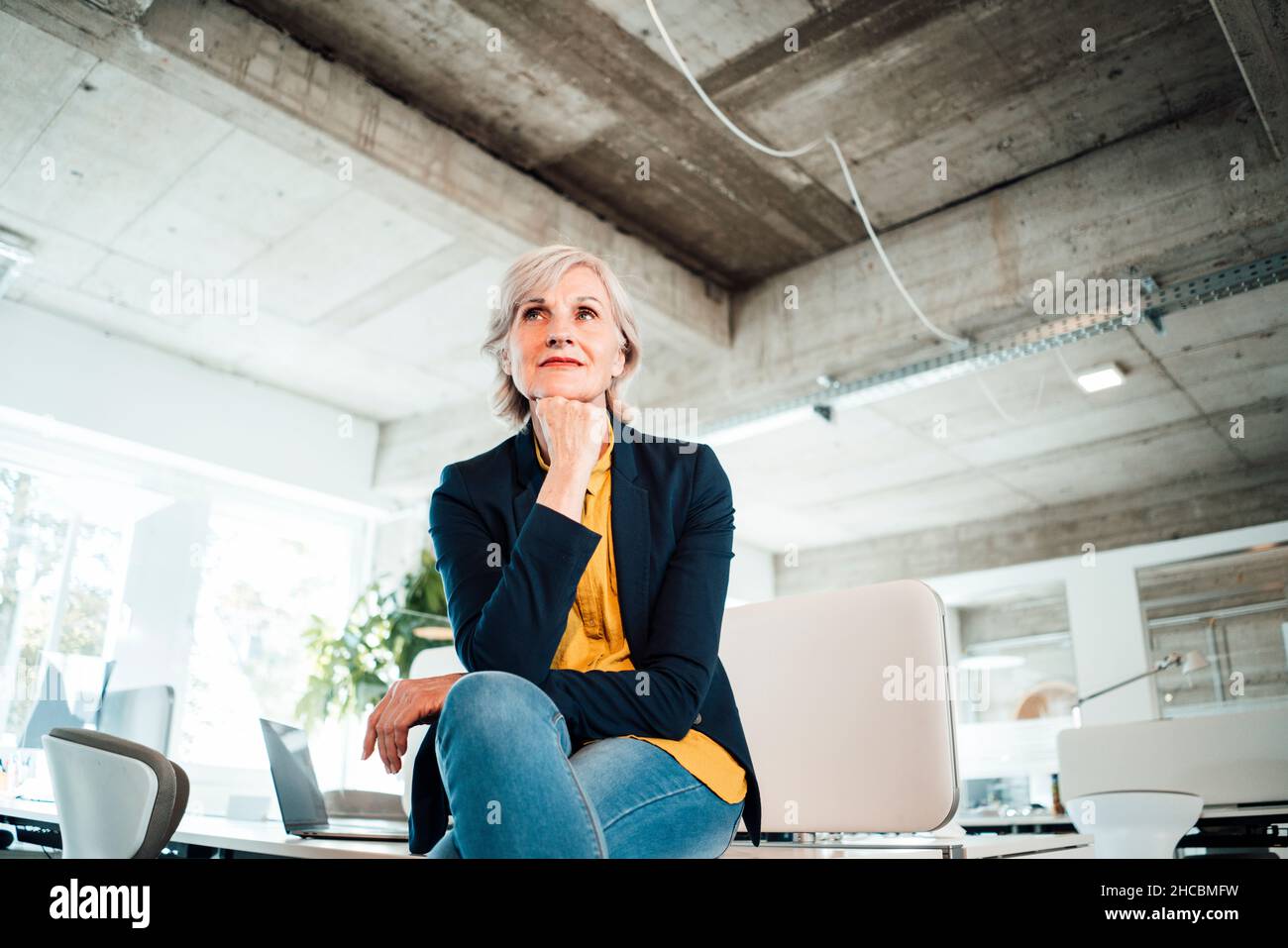 Durchdachte Geschäftsfrau mit Laptop am Arbeitsplatz Stockfoto