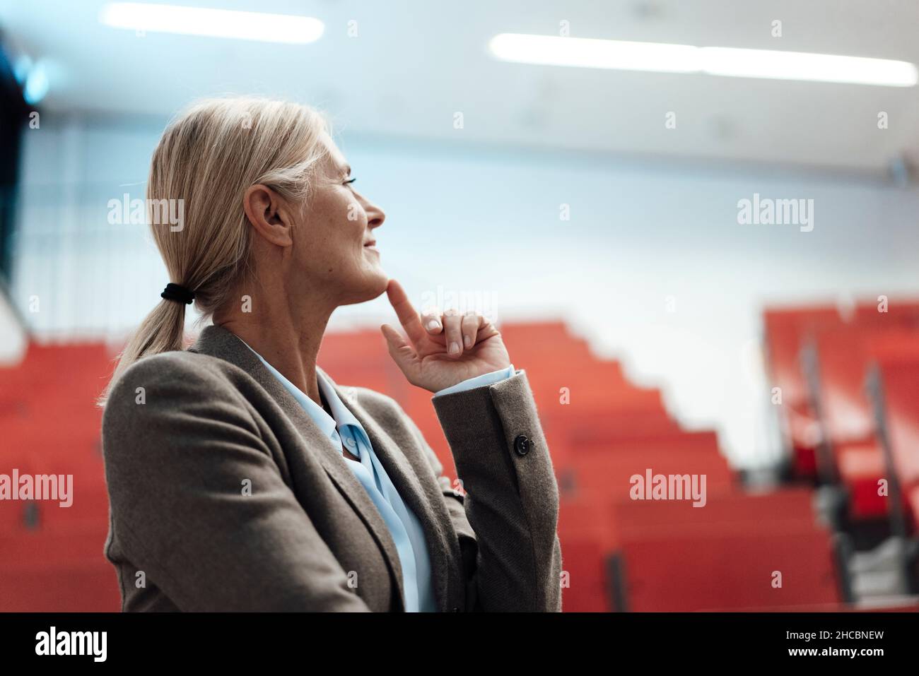 Geschäftsfrau mit der Hand am Kinn im Auditorium des Büros Stockfoto