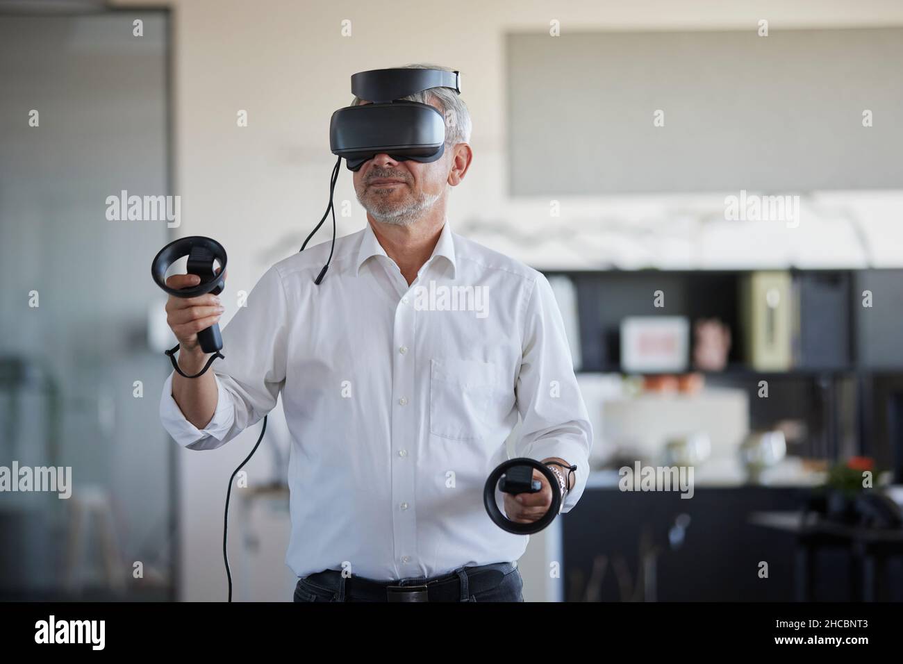 Geschäftsmann, der am Arbeitsplatz mit einem virtuellen Headset spielt Stockfoto