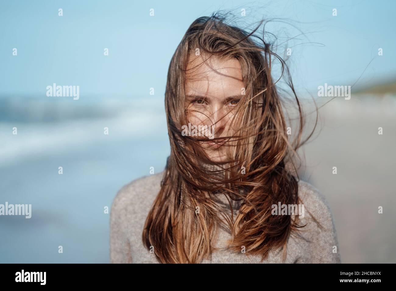 Mann, der mit gekreuzten Armen am Strand steht Stockfoto