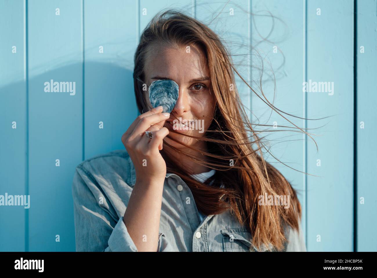 Lächelnde Frau, die das Auge mit Stein bedeckt Stockfoto