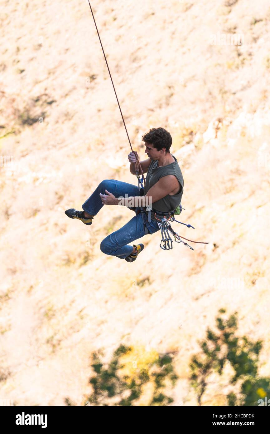 Mann mit Sicherheitsgurt, der den Felsberg klettert Stockfoto