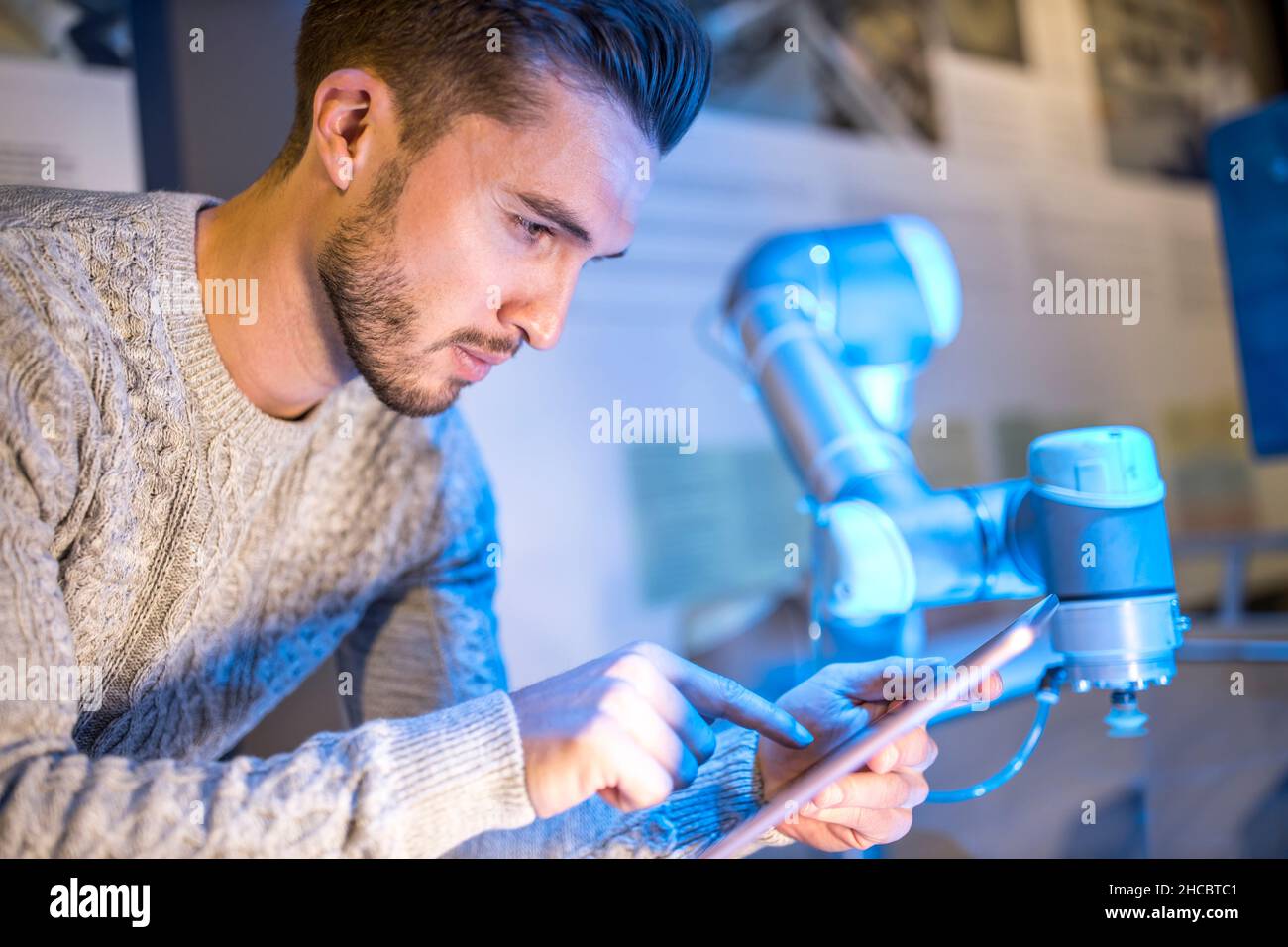 Techniker, der in der Werkstatt einen Tablet-PC in der Nähe des Roboterarms verwendet Stockfoto