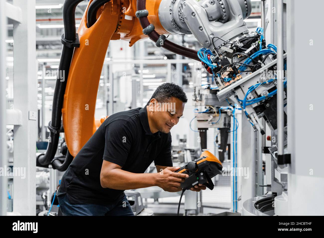 Wartungstechniker, der den Roboterarm in der Elektrofabrik betreibt Stockfoto