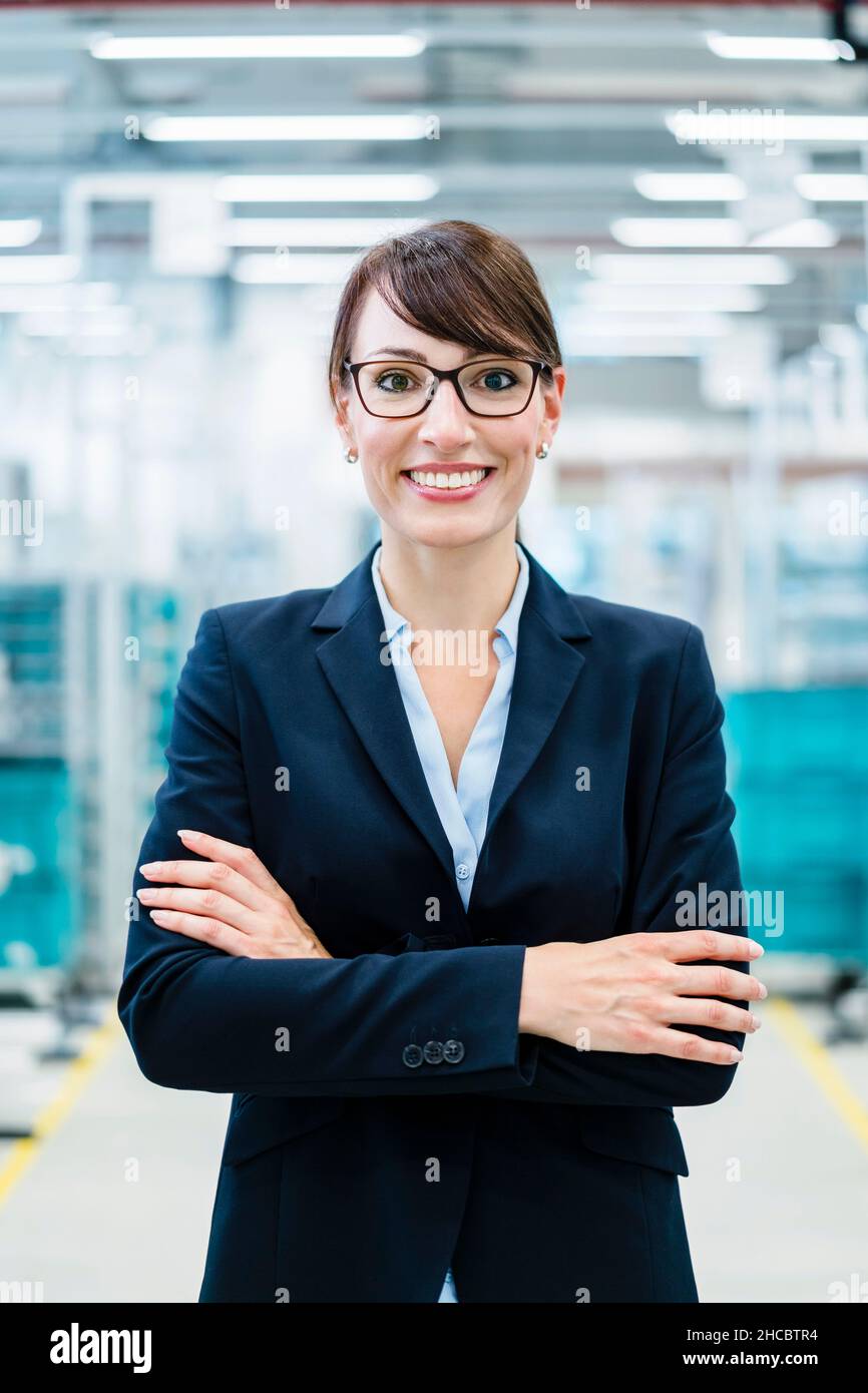 Lächelnde Geschäftsfrau mit gekreuzten Armen auf die Industrie Stockfoto