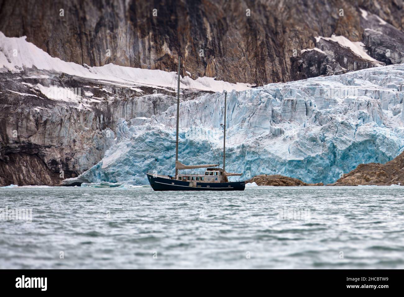 Schiff im Ozean auf einem verschneiten Berghintergrund an einem Wintertag in Spitzbergen Stockfoto