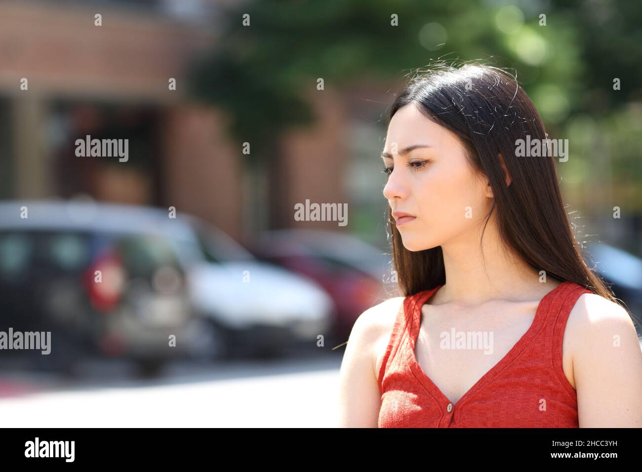 Seriöse asiatische Frau in Rot, die weg schaut, wenn sie auf der Straße geht Stockfoto