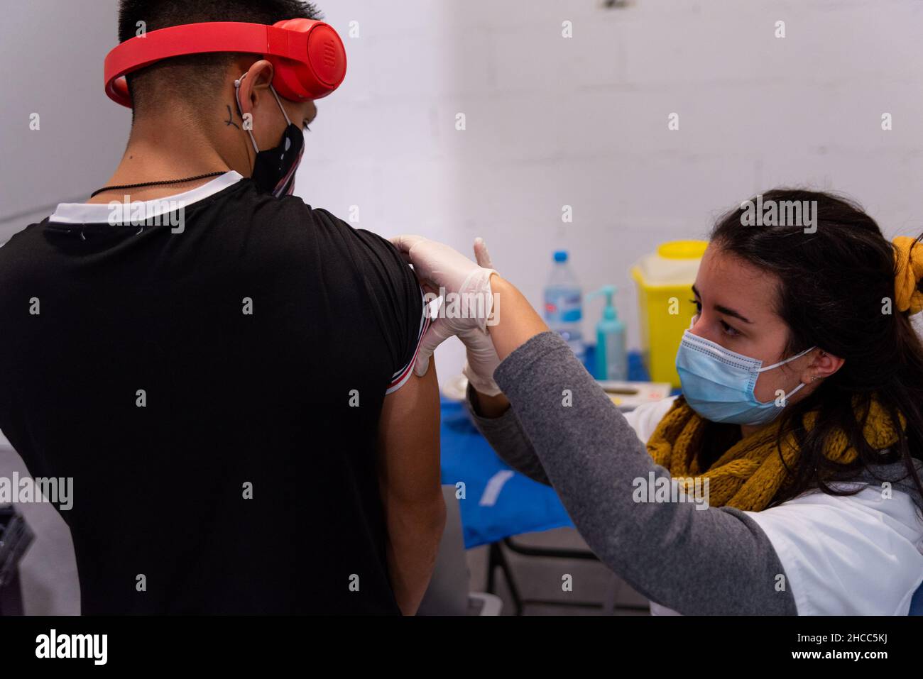 Ein junger Teenager, der Kopfhörer trägt, erhält am 22. Dezember 2021 in einem Impfzentrum in Barcelona, Spanien, eine Dosis Covid-19-Impfstoff. Stockfoto