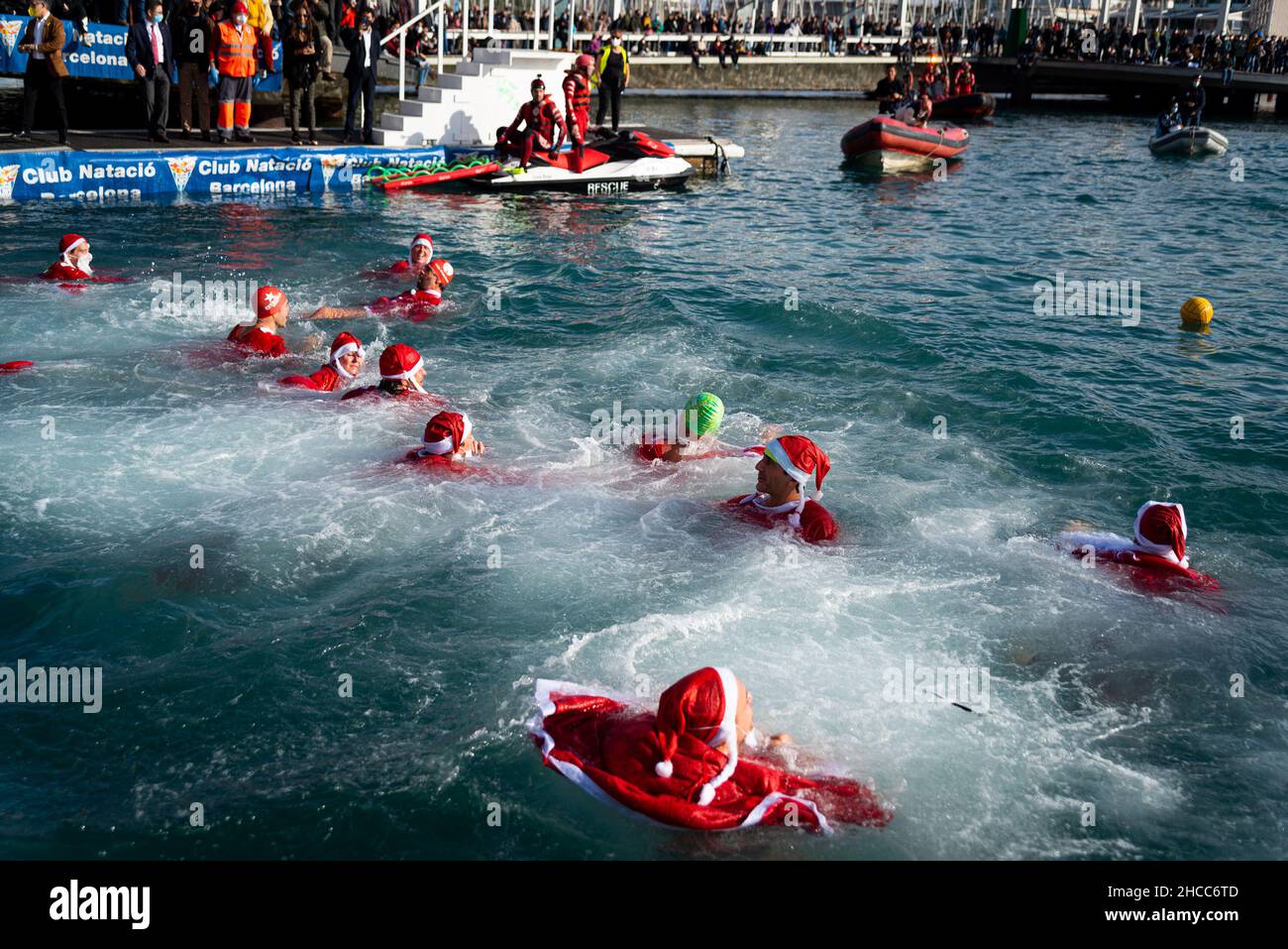 Die Menschen, die als Weihnachtsmann auf dem traditionellen Weihnachtsschwimmwettbewerb „Copa Nadal“, Spaniens ältestem Freiwasser-Schwimmwettbewerb, an Weihnachten in Barcelon gekleidet sind Stockfoto
