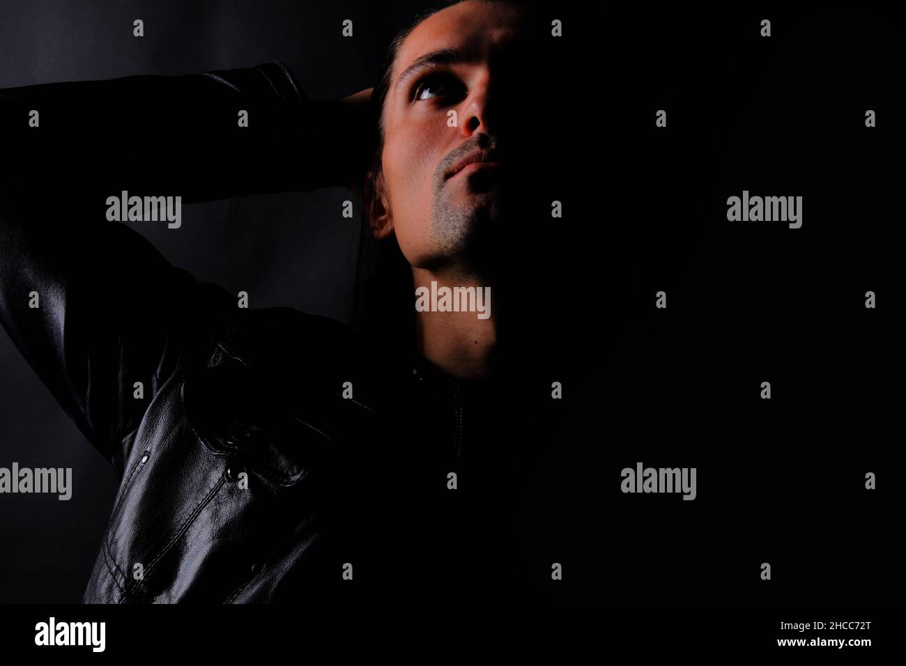 Porträt eines Mannes mit Schatten auf seinem Gesicht auf einem dunklen Hintergrund Stockfoto