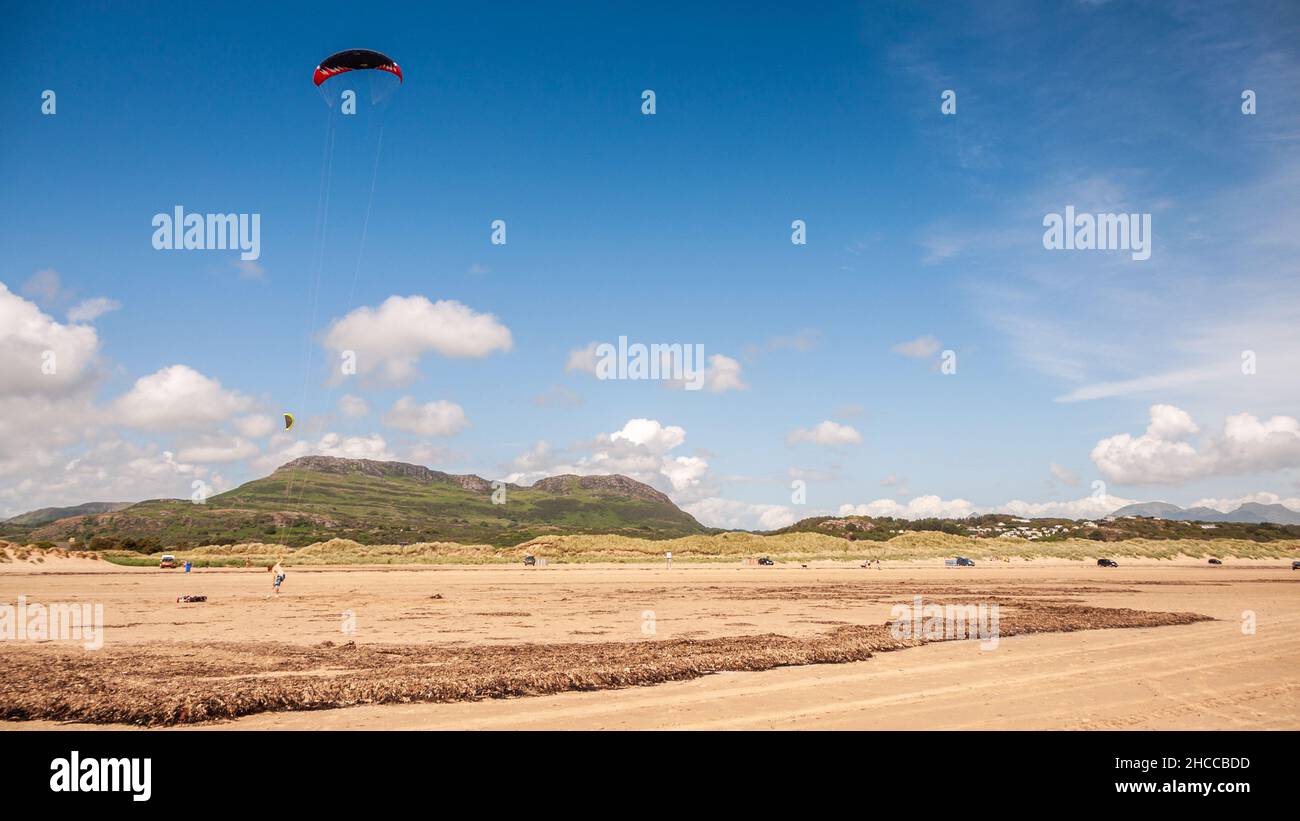 Am Strand von Black Rock Sands in der Nähe von Porthmadog fliegen die Leute mit den Bergen von Snowdonia. Stockfoto
