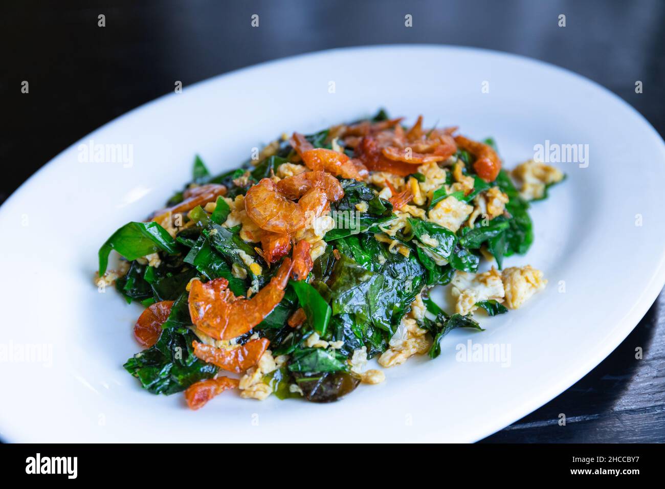 Gebratene Melinjo-Malindjoblätter mit Ei und knusprig getrockneten Garnelen, thailändisches Essen umrühren Stockfoto