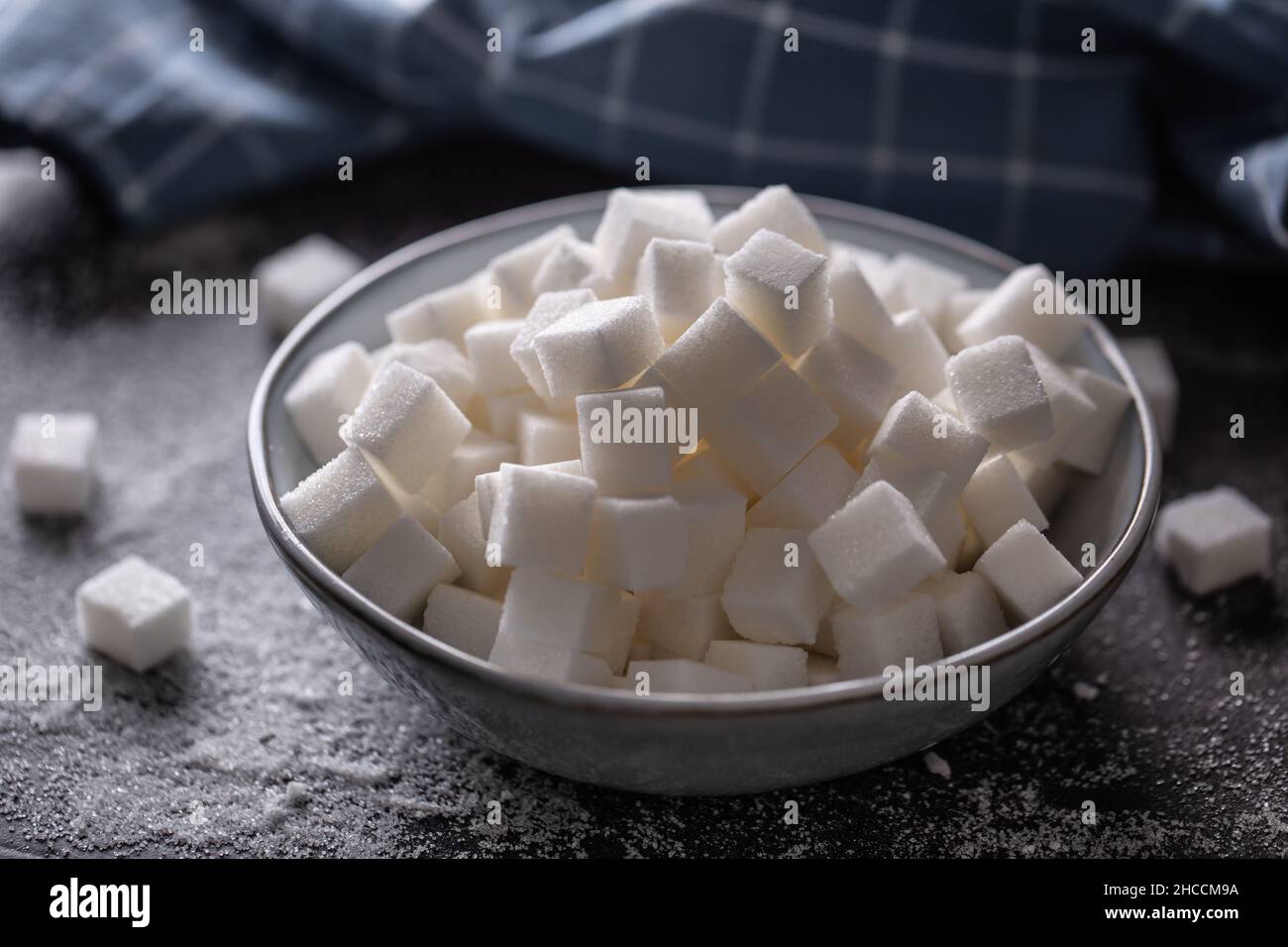Weiße Zuckerwürfel in einer blauen Schüssel auf dem Tisch. Stockfoto