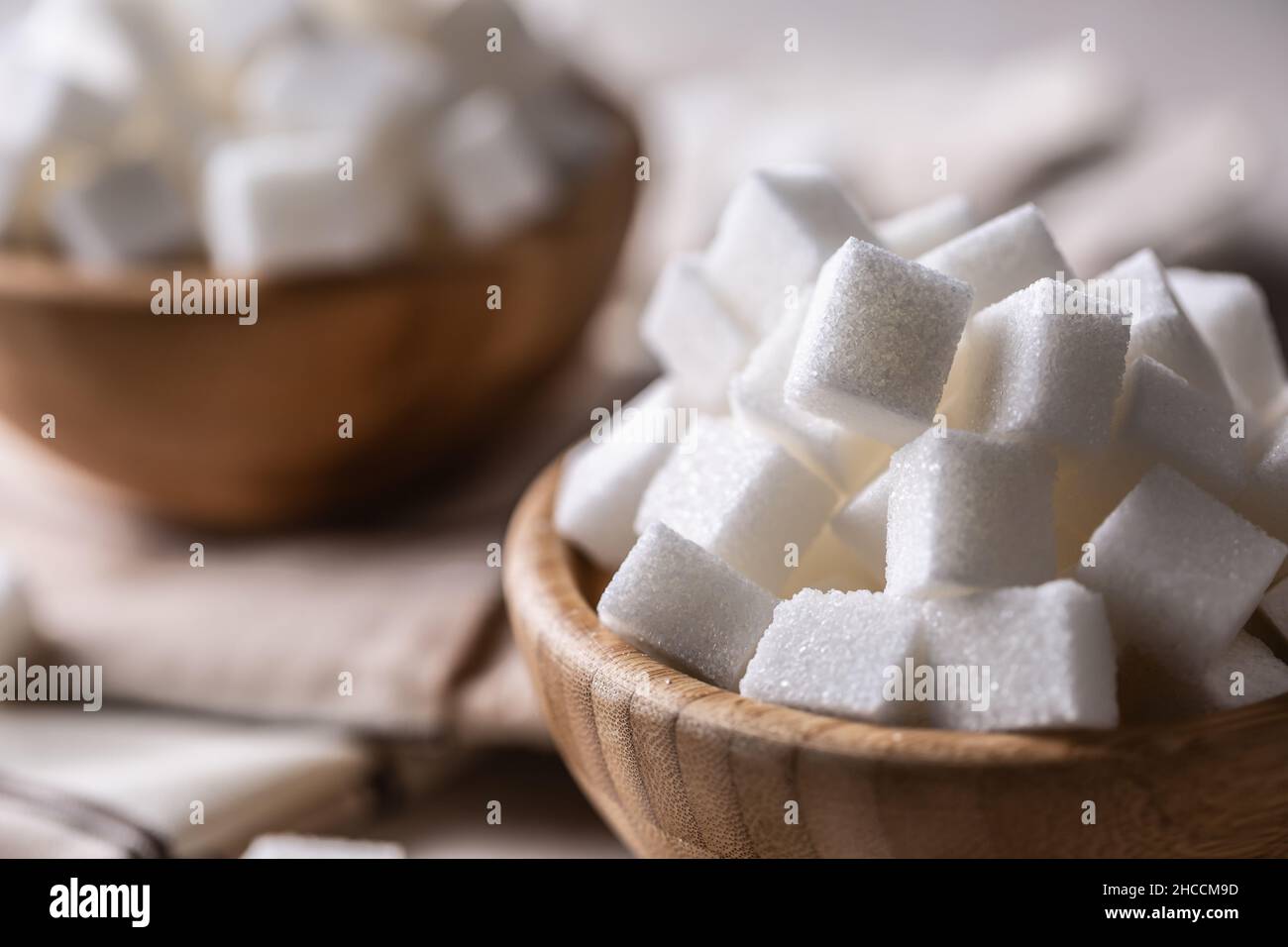 Weiße Zuckerwürfel in einer Holzschüssel auf dem Tisch. Stockfoto