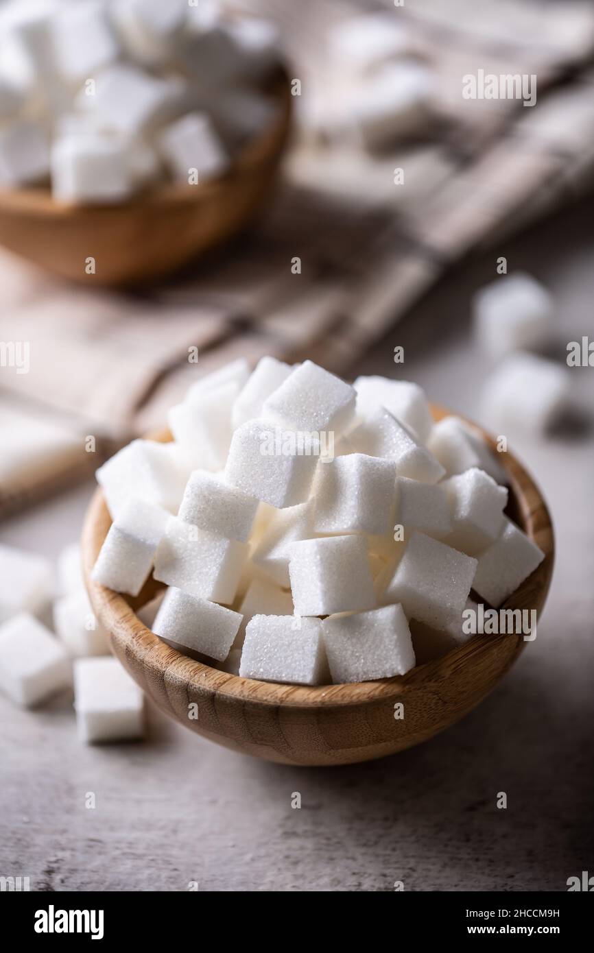 Weiße Zuckerwürfel in einer Holzschüssel auf dem Tisch. Stockfoto
