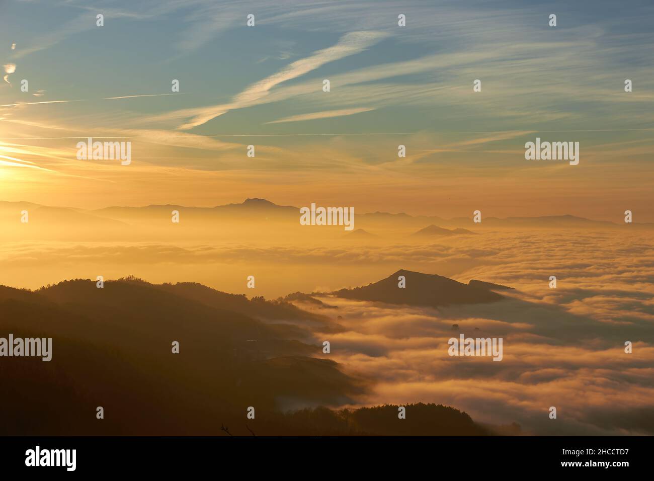 Landschaft der Küste mit einem Meer von Wolken von einem Berg aus gesehen, warme Sonnenuntergangslichter über den niedrigen Wolken, die das Meer bedecken Stockfoto