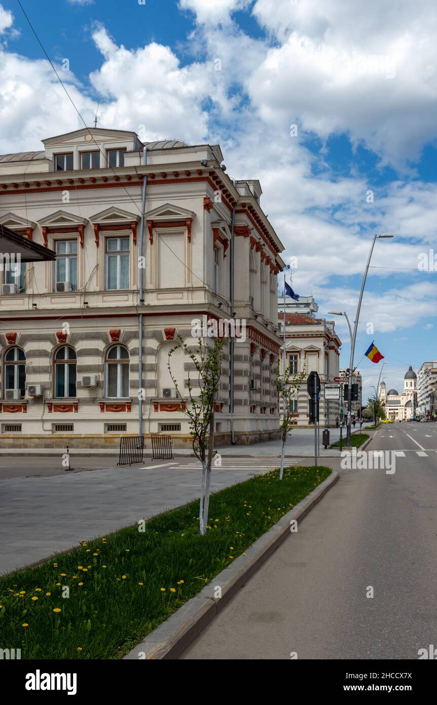 Bacău, Rumänien-2. Mai 2021: Beeindruckendes Gebäude, historisches Denkmal, Verwaltungspalast in Bacău, Moldau, Seitenblick mit rumänischer Flagge Stockfoto