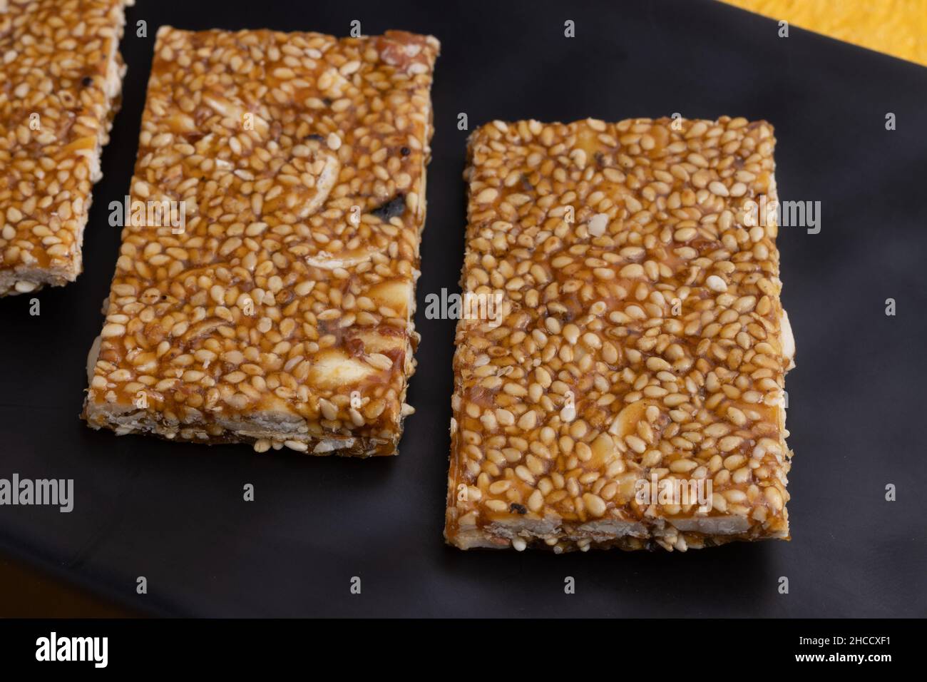 Süßigkeiten Mithai aus Indien isoliert auf gelbem Hintergrund für Makar Sankranti Lohri Gajak auch bekannt als Gur Gajjak Gazak Kachak Til Patti Stockfoto