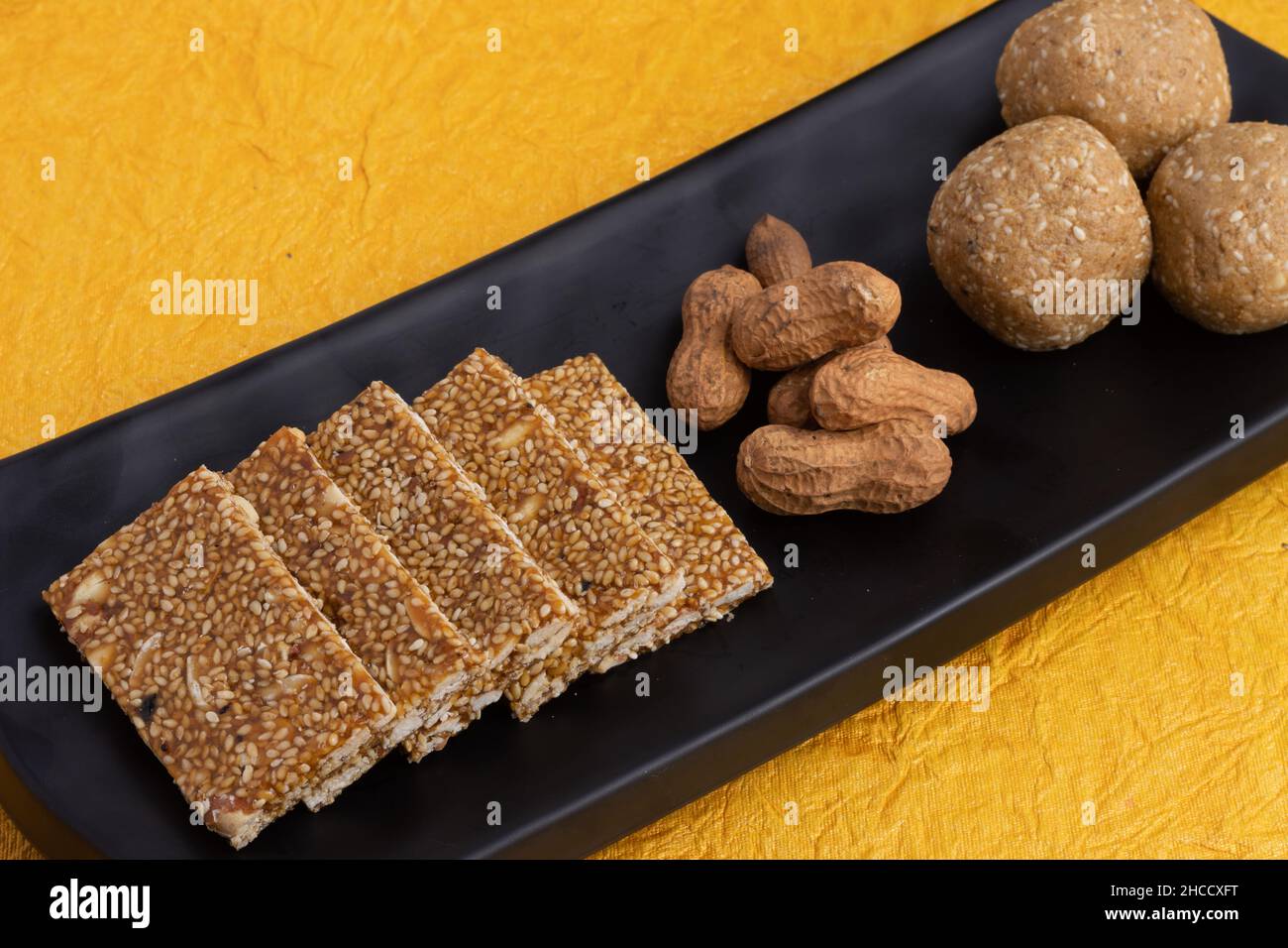 Süßigkeiten Mithai isoliert auf gelbem Hintergrund für Makar Sankranti Lohri Gajak auch bekannt als Gur Gajjak Gazak Kachak Til Patti Erdnüsse Mandeln Stockfoto