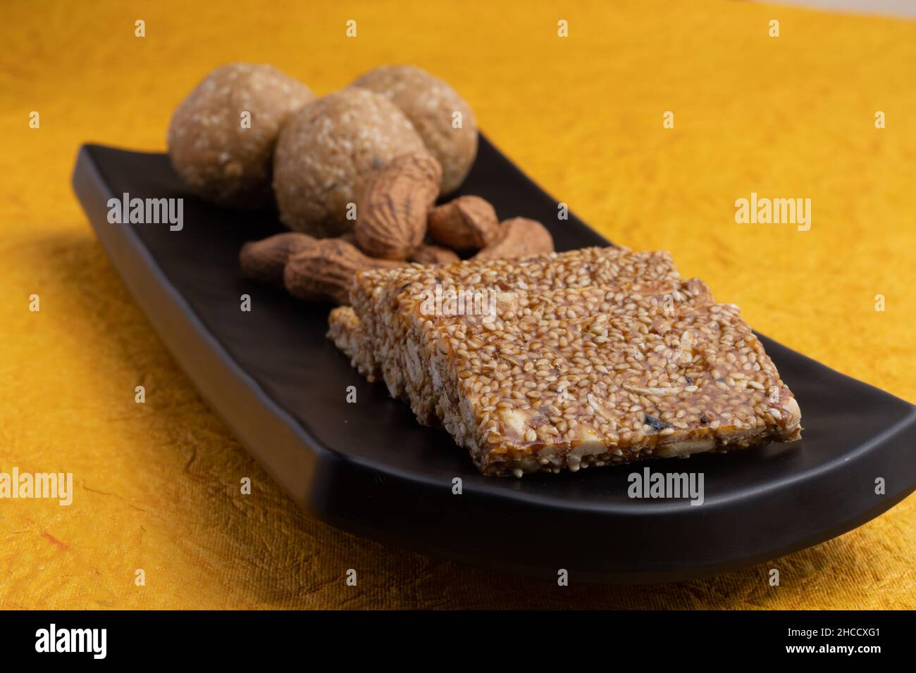 Indische traditionelle Süßigkeiten Mithai isoliert auf gelbem Hintergrund für Makar Sankranti Lohri Gajak auch bekannt als Gur Gajjak Gazak Kachak Til Patti Stockfoto