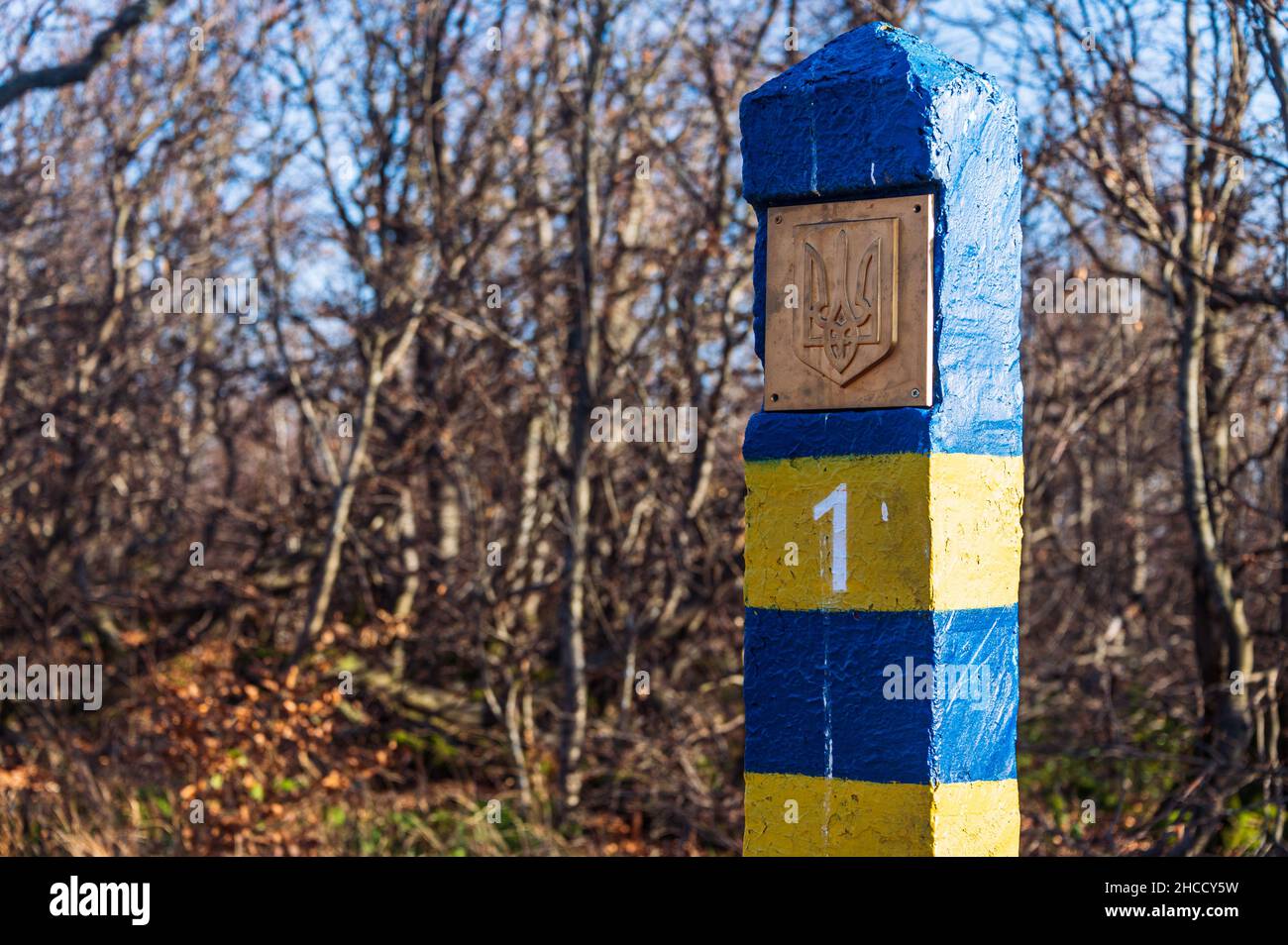Ukrainisch blau und gelb Nummer eins Grenzsäule mit Wappen. Im Hintergrund der blaue Himmel und Bäume, Sträucher und Gras Stockfoto