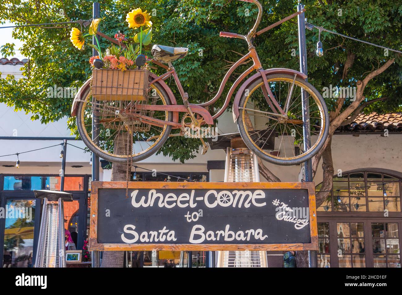 Ein Fahrrad, das über einem Schild für ein neues Restaurant hängt. Stockfoto