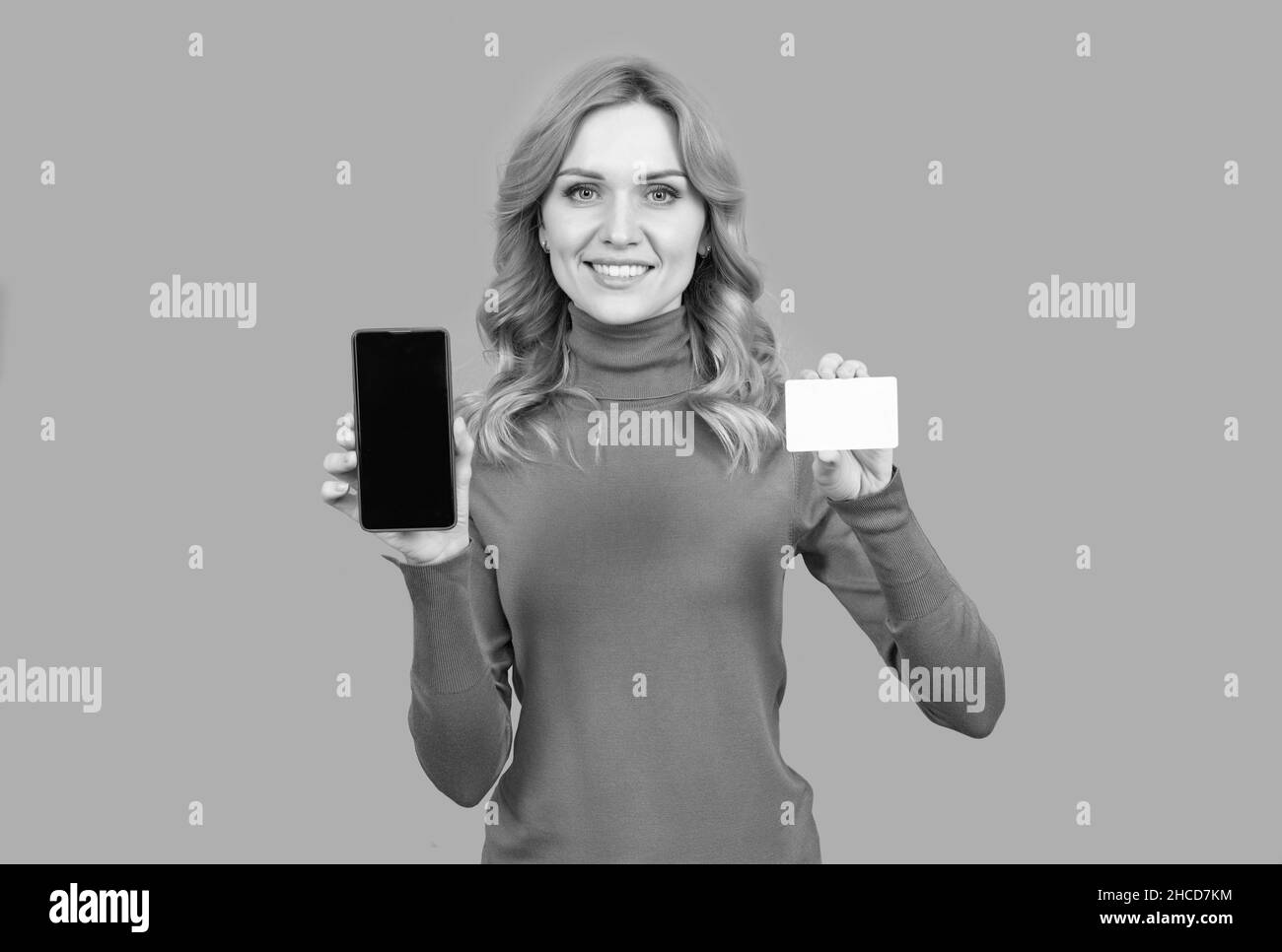 Frau halten Treuekarte und Smartphone zum Online-Shopping grauen Hintergrund Kopie Raum, Rabatt Stockfoto