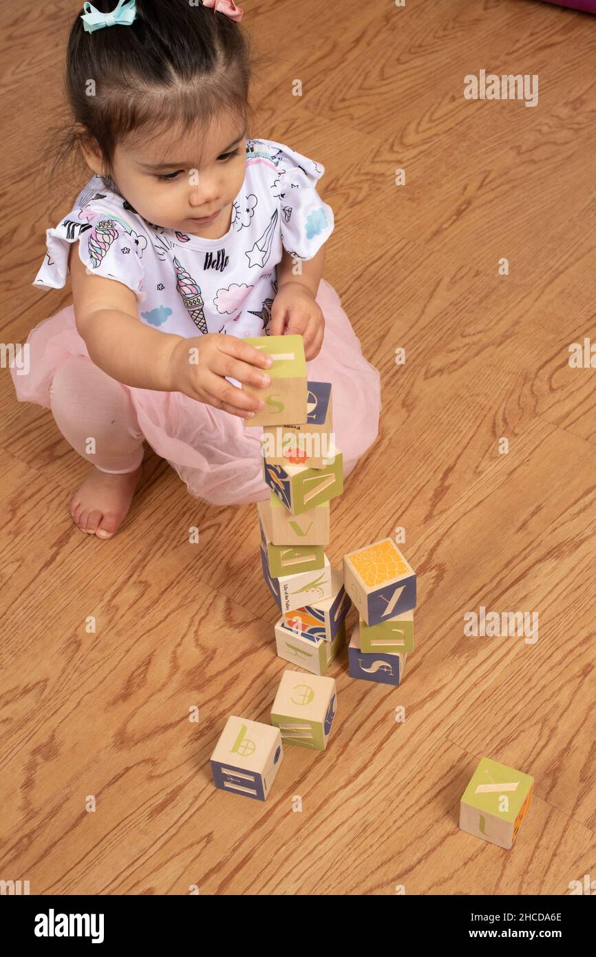 17 Monate altes Kleinkind Mädchen macht Turm aus Holzblöcken Stockfoto