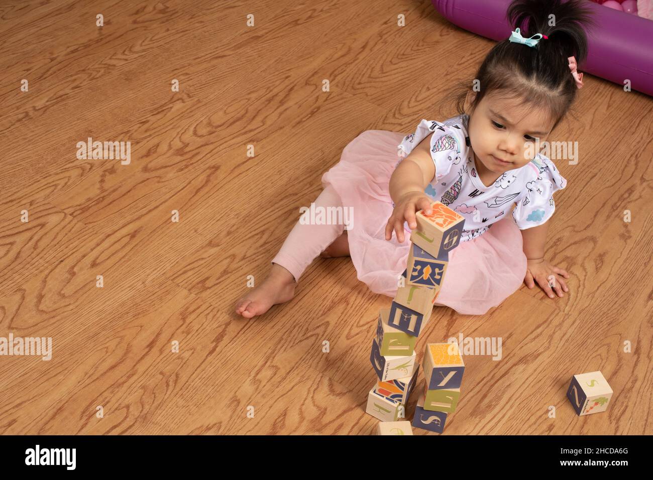 17 Monate altes Kleinkind Mädchen macht Turm aus Holzblöcken Stockfoto