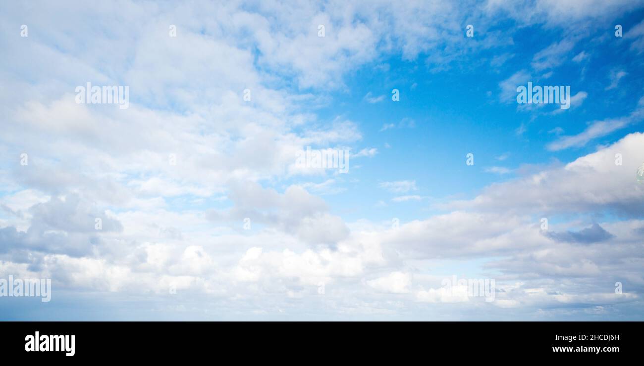 Blauer Himmel mit weißen Altocumuluswolken auf einem natürlichen Hintergrundfoto am Tag Stockfoto