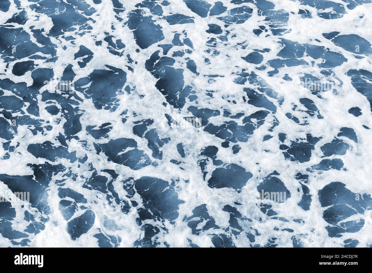 Blaues Uferwasser mit Wellen und Schaum, Draufsicht, natürliche Hintergrundfotostruktur Stockfoto