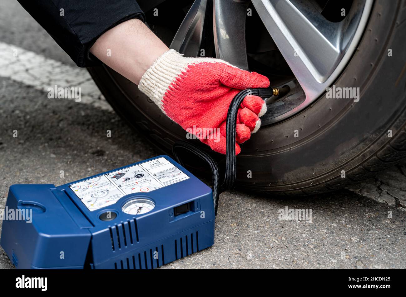 Mann, der Luft in den Reifen einfüllt. Autofahrer Prüft Den Luftdruck. Stockfoto
