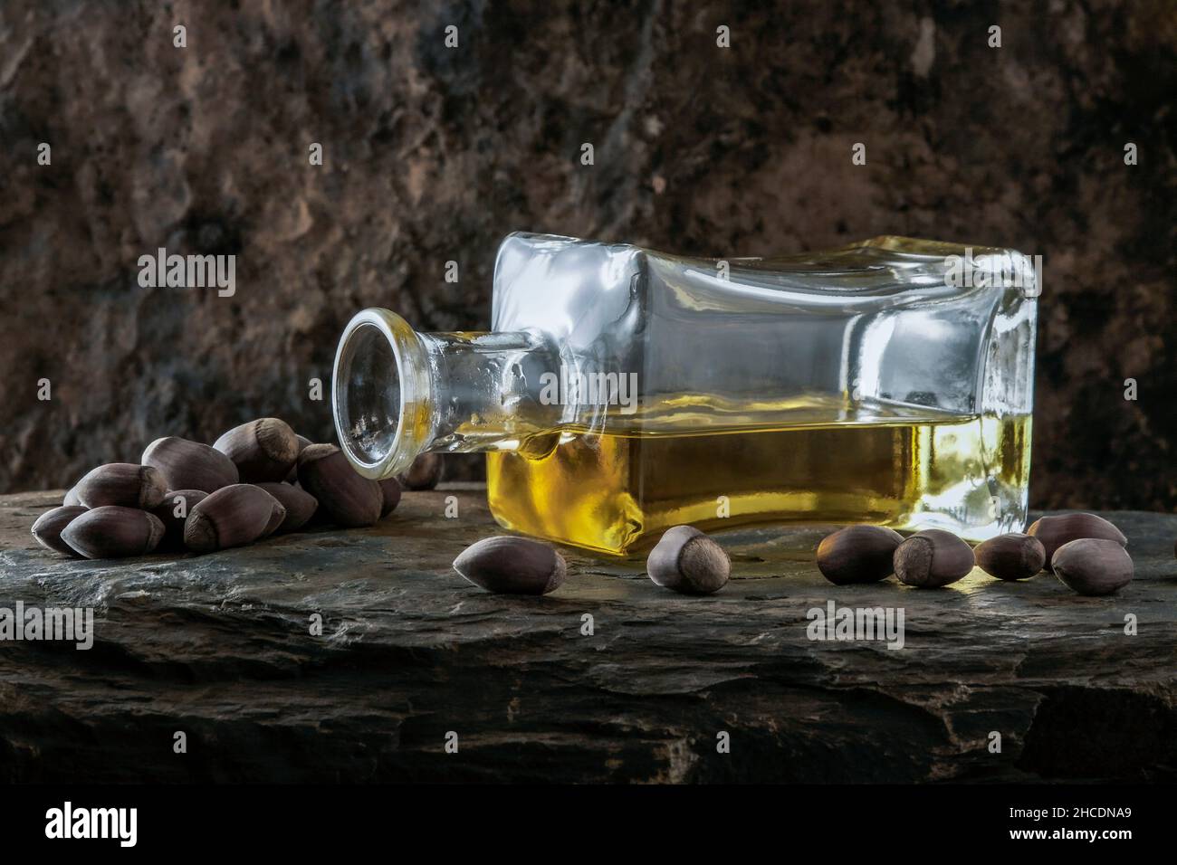 Haselnussöl mit Haselnüssen auf steinernem Hintergrund Stockfoto