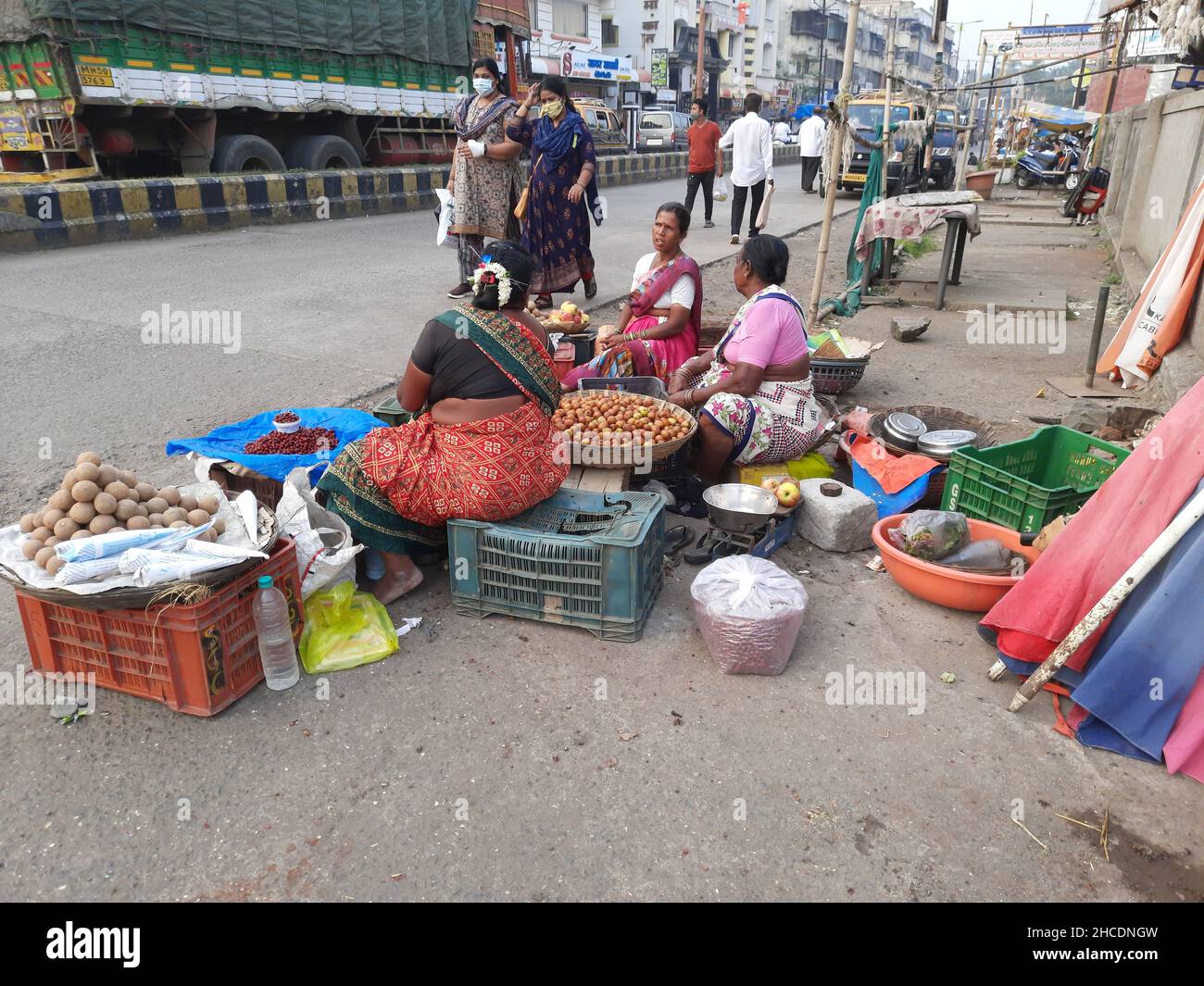 Weibliche Verkäuferin, die Früchte auf dem Bürgersteig im Bundesstaat Alibag, Maharashtra, Indien, verkauft Stockfoto