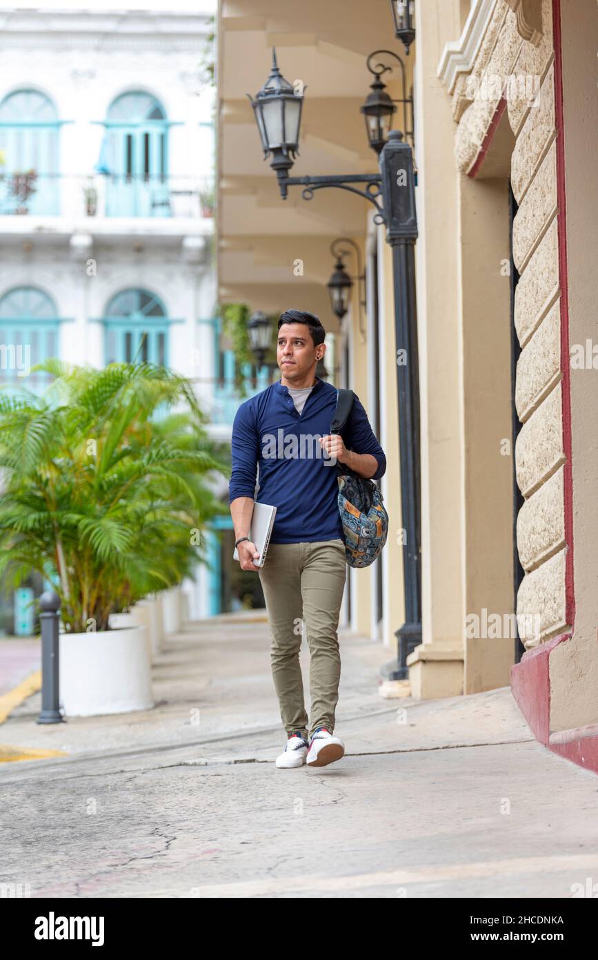 Junger Latino-Mann, der mit seinem Laptop die Straße entlang geht, Panama City, Mittelamerika Stockfoto