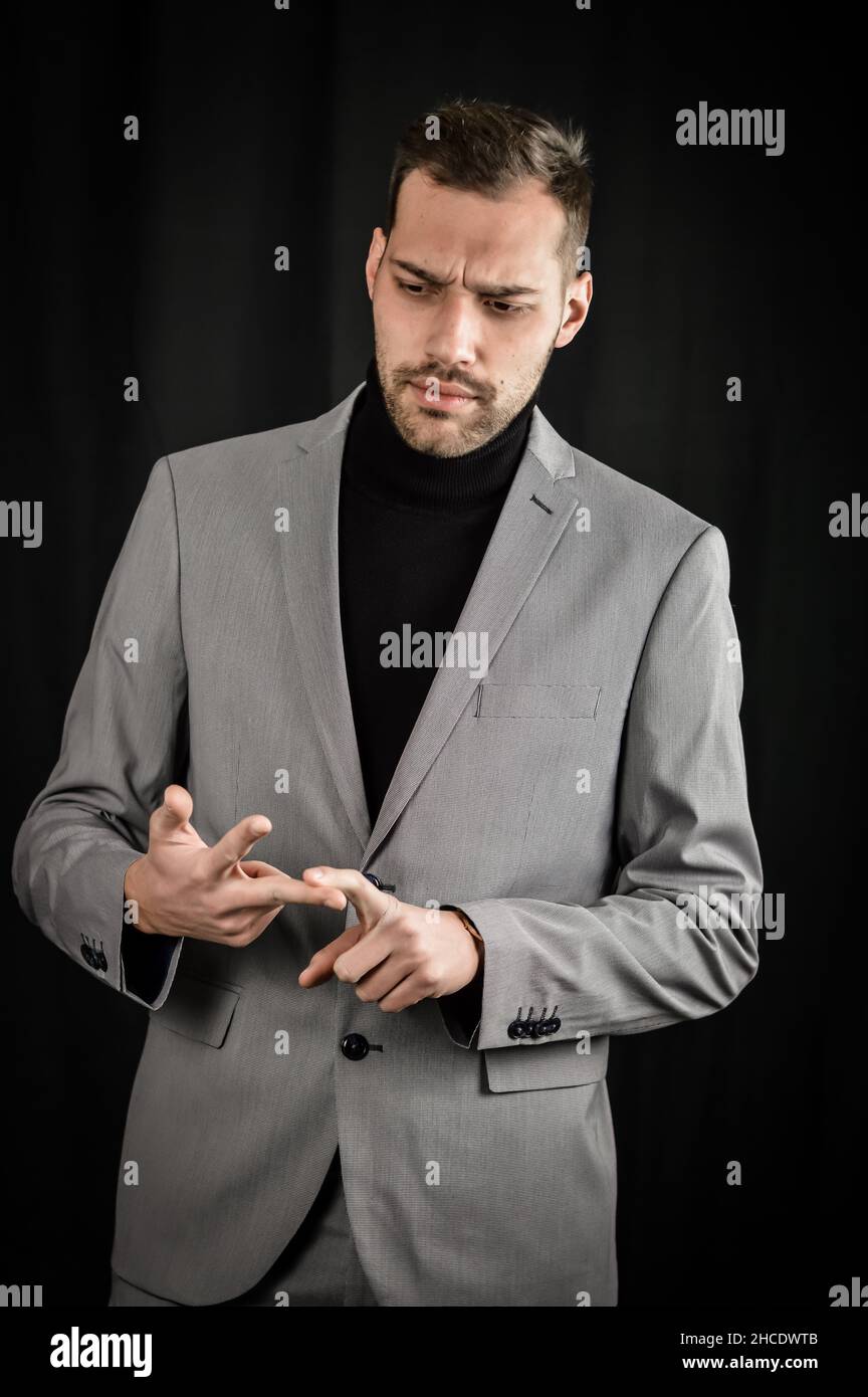 Porträt eines jungen Geschäftsmannes in grauem Anzug, der Dinge aufzählt, indem er auf seinen Fingern zählt und gestikulierend wirkt besorgt Stockfoto