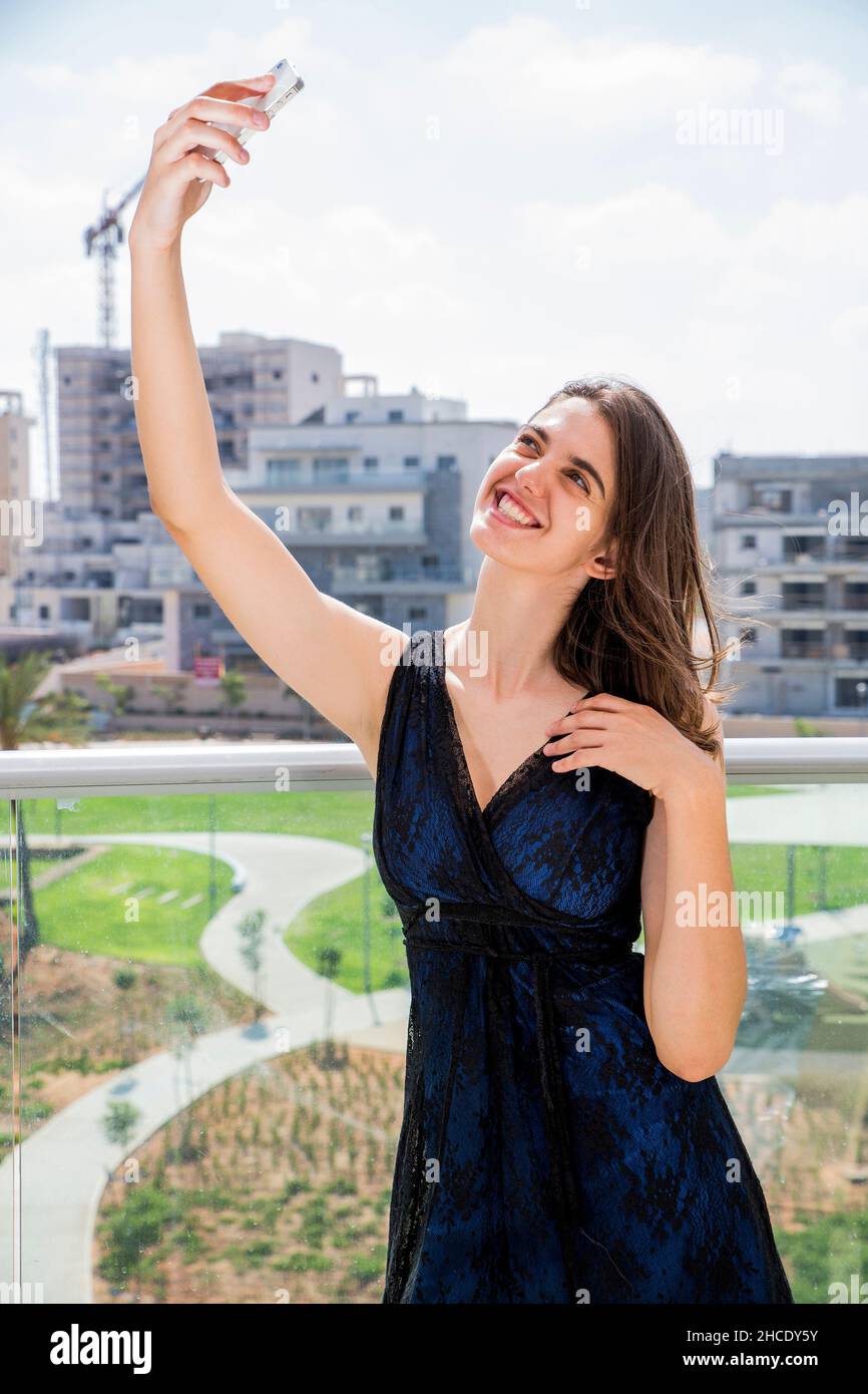 Junge Frau im Abendkleid nimmt ein Selfie im Freien Stockfoto