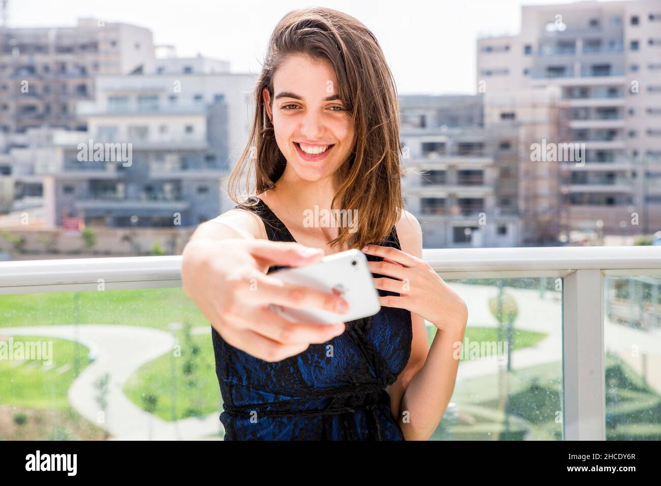 Junge Frau im Abendkleid nimmt ein Selfie im Freien Stockfoto