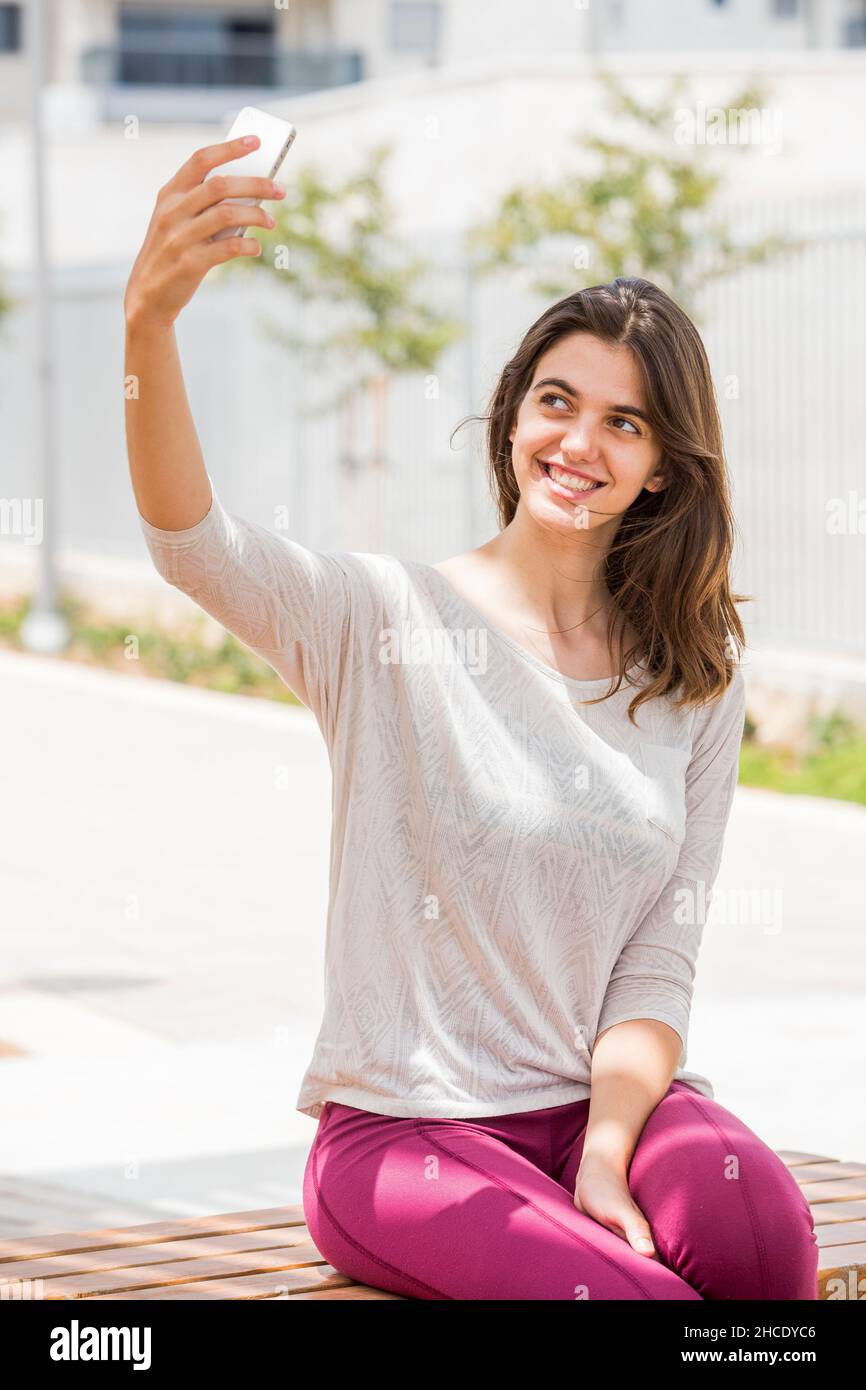 Junge Frau in legerer Sportkleidung nimmt ein Selfie draußen Stockfoto