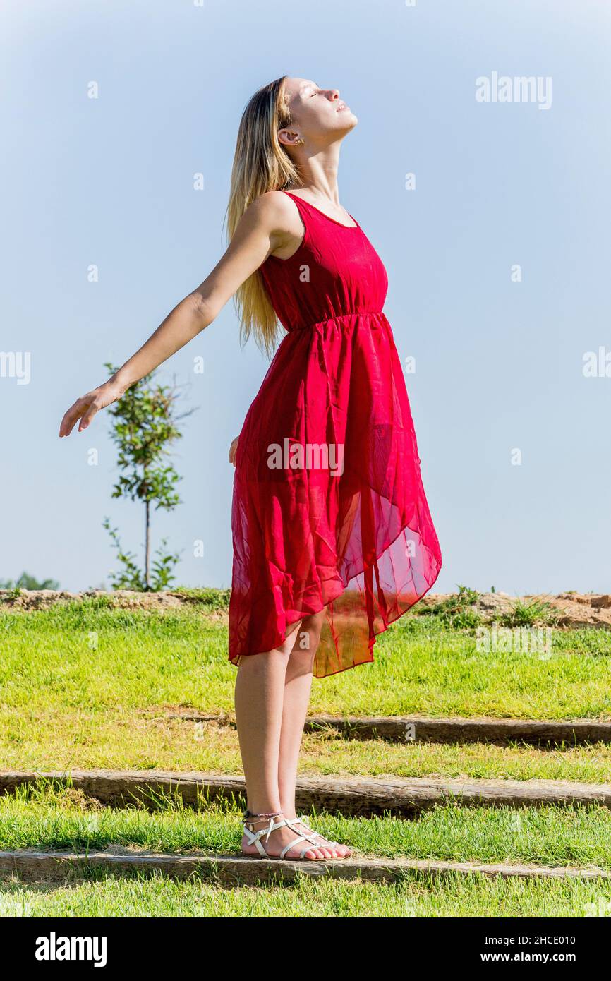 Junge Frau in rotem Kleid genießt die frische Luft draußen Stockfoto