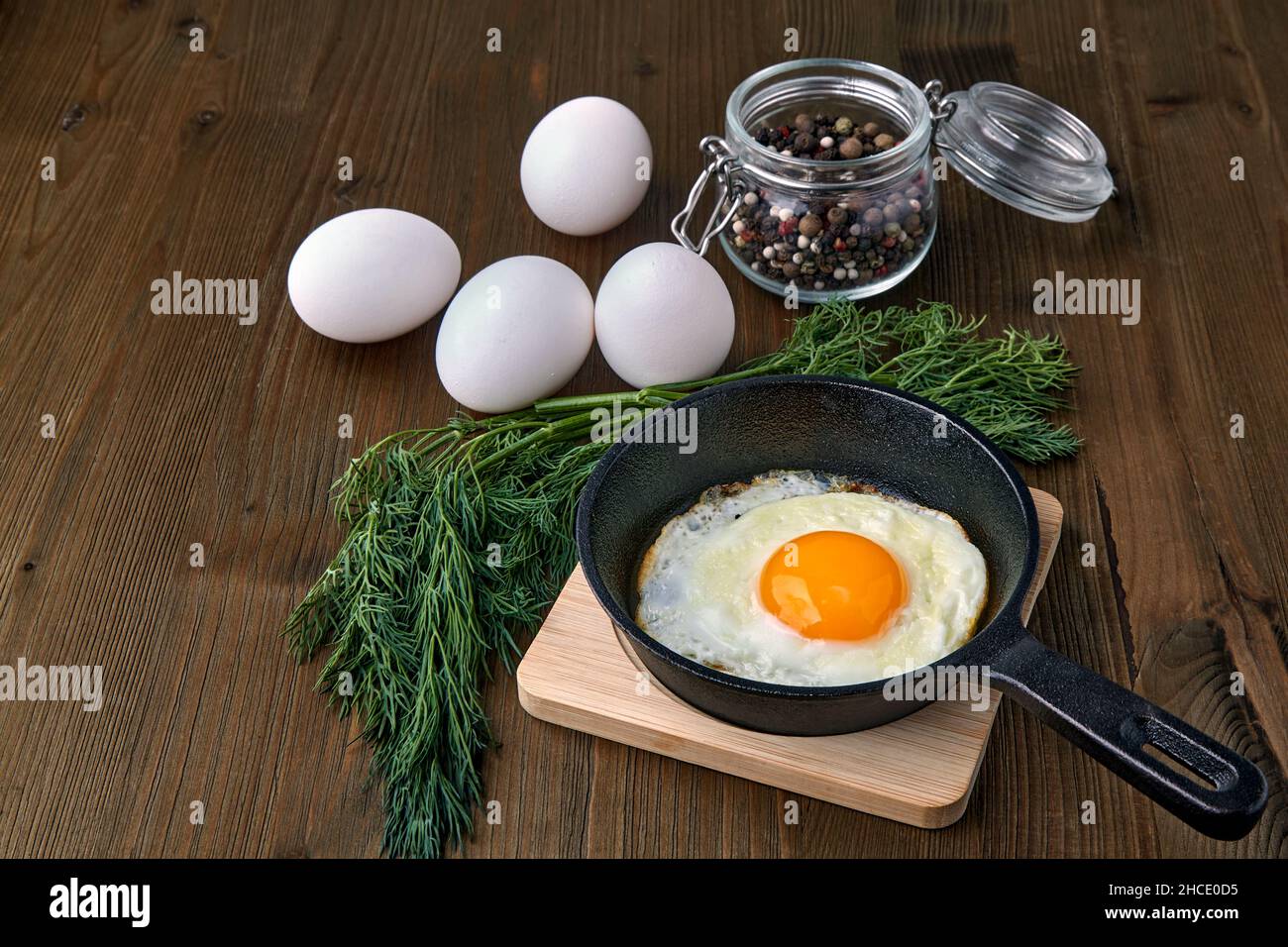 Spiegeleier in einer kleinen Pfanne mit einem Ständer, einem Haufen Dill Stockfoto