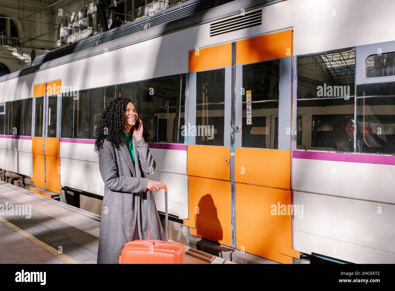 Fröhliche afroamerikanische Sängerin in Kopfhörern mit Mikrofon Blick auf das Smartphone, während die Aufnahme des Songs im professionellen Aufnahmestudio mit Stockfoto
