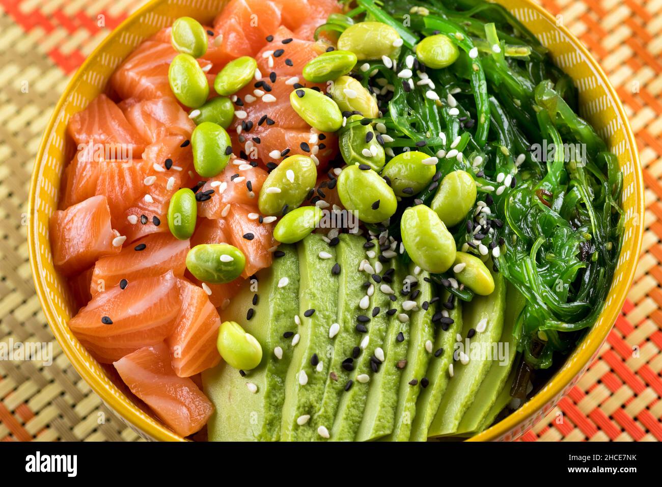 Von oben appetitlich gesunde Poke Schüssel mit gehacktem Lachs und leckeres Gemüse auf den Tisch gelegt Stockfoto