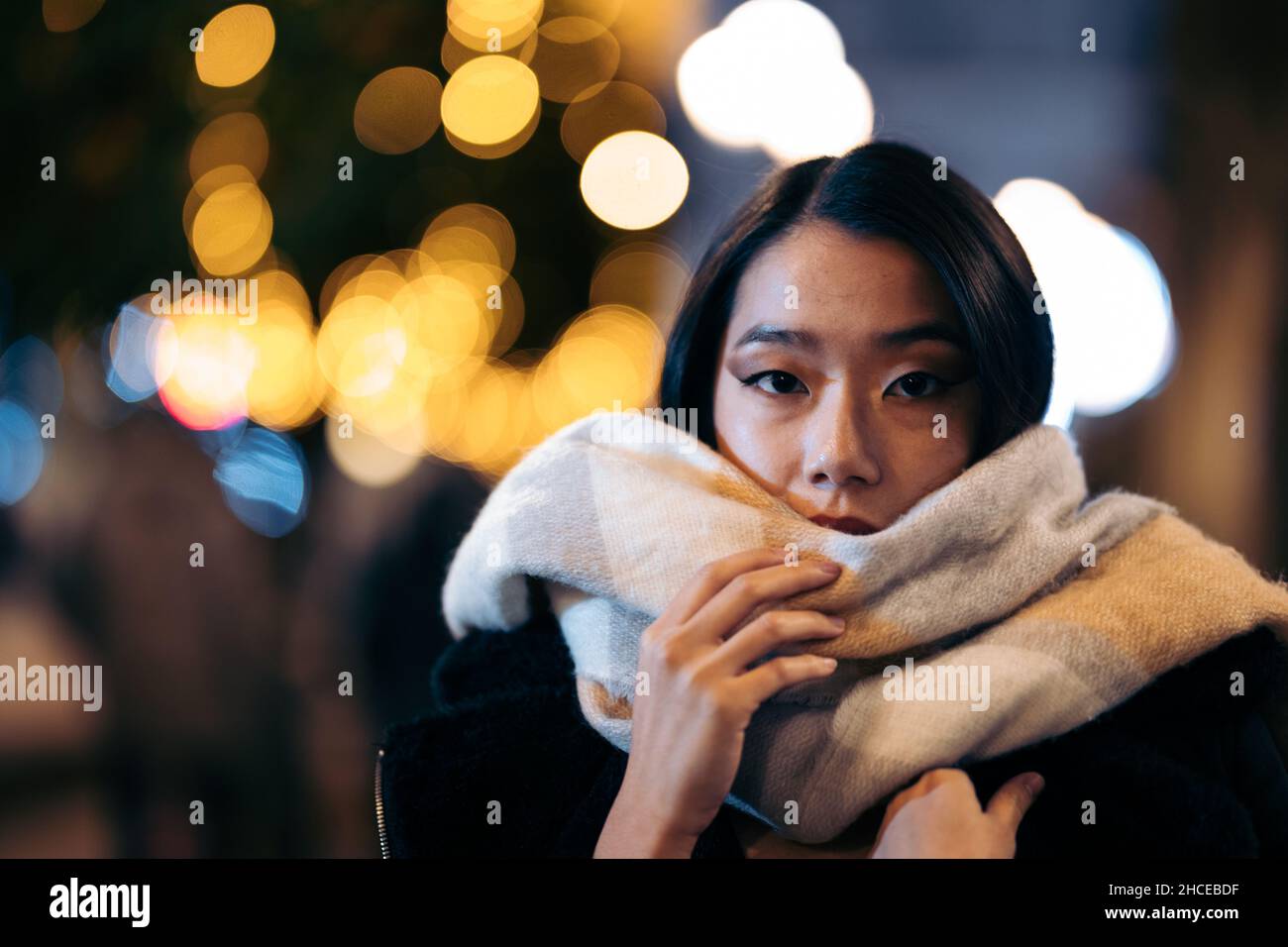 Junge asiatische Frau mit Schal auf der Straße in der Nacht Stockfoto