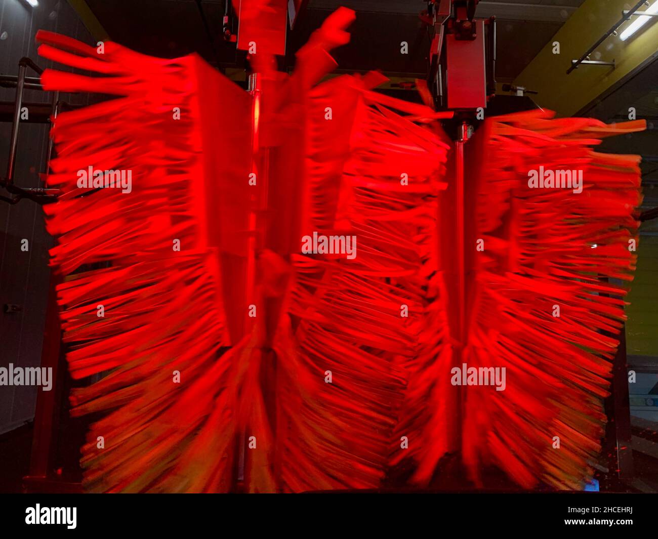 In der automatischen Transporttunnelwaschanlage. Blick vom Innenraum des Autos, rote rotierende Trockenbürsten. Stockfoto