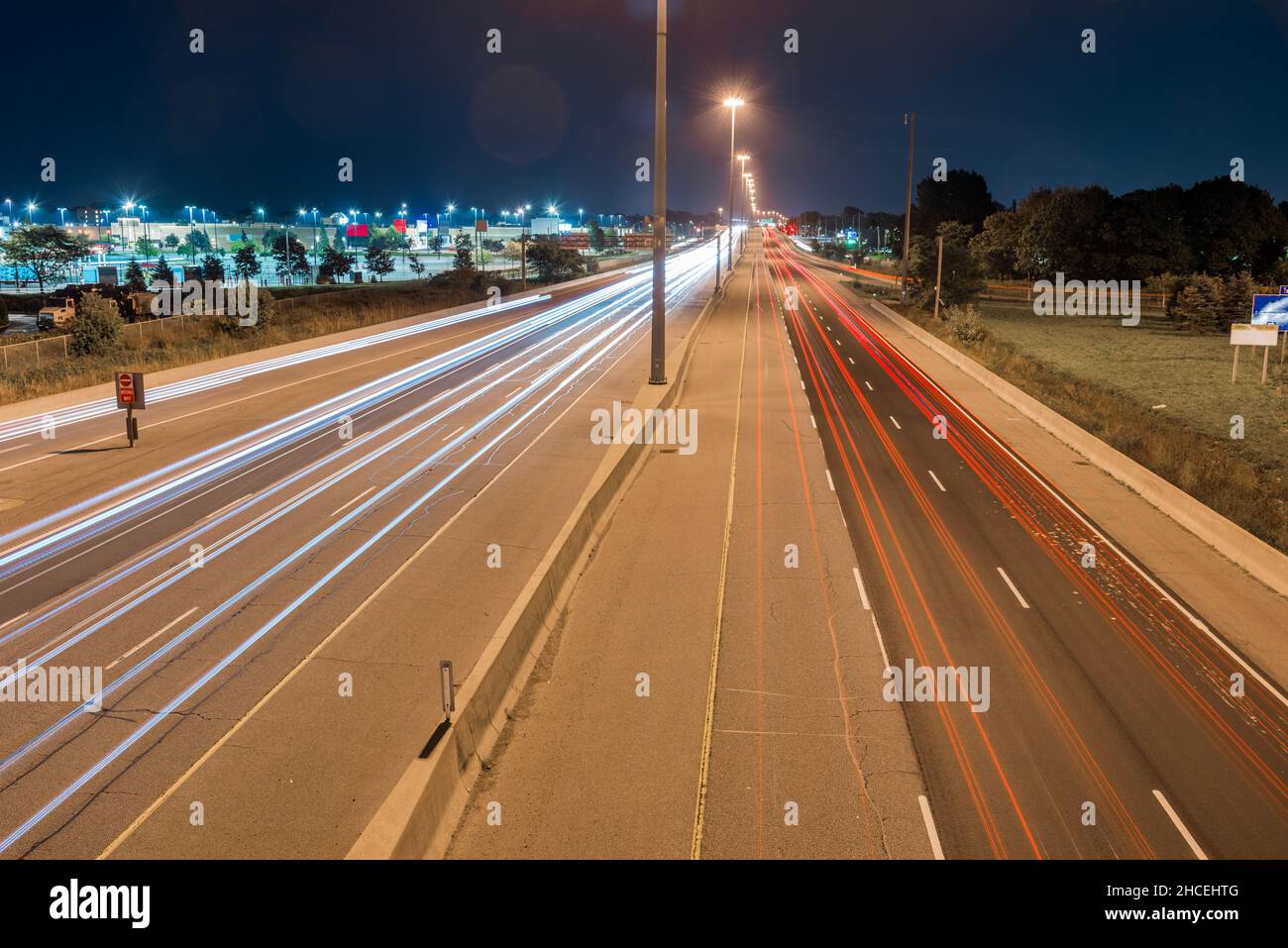 Nachtsicht von einer Autobahn mit leichten Wegen, die von vorbeifahrenden Fahrzeugen verlassen werden Stockfoto