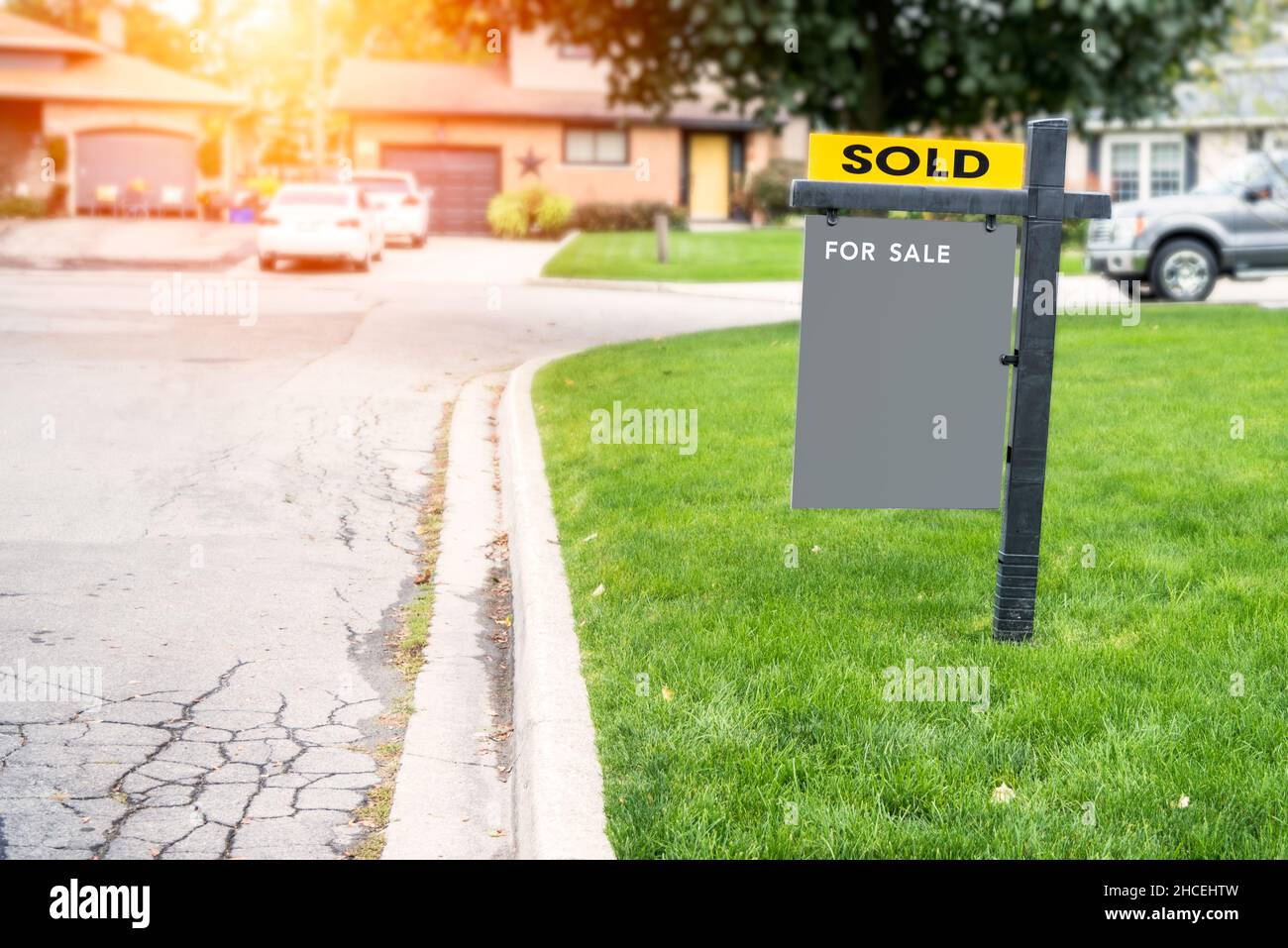 Leeres Immobilienschild auf einem Rasen vor einem verkauften Haus Stockfoto